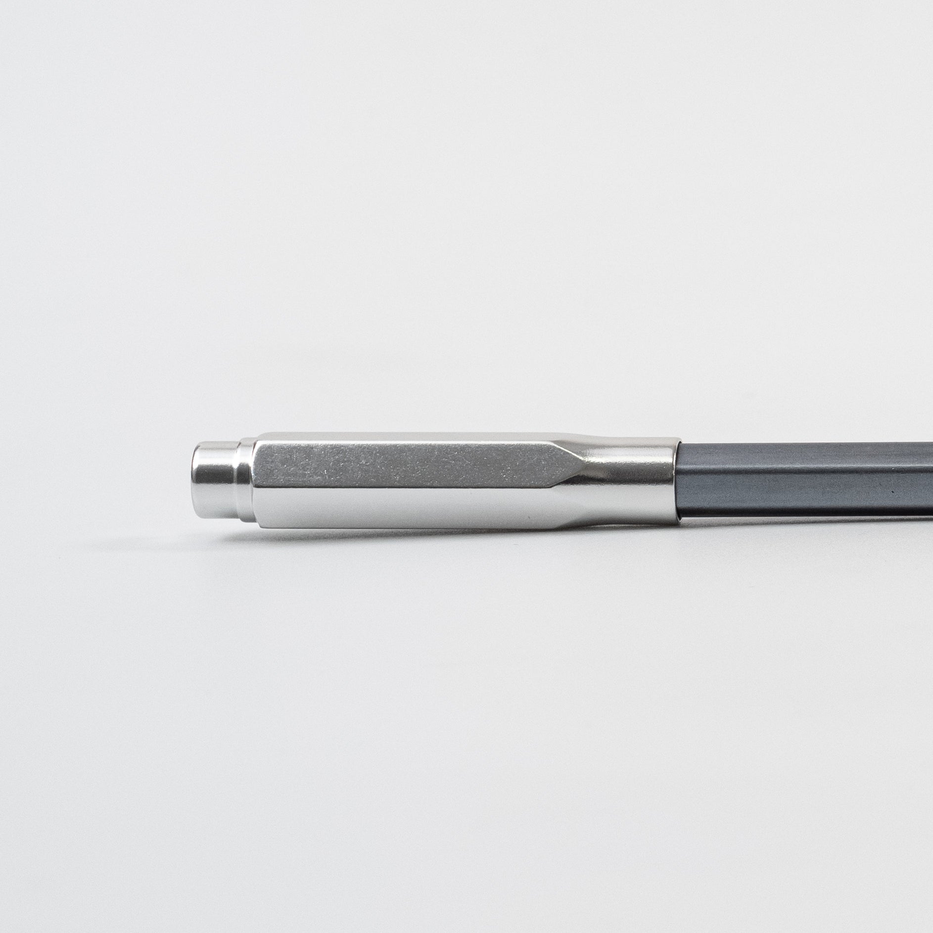 A black, gold, and silver Blackwing Point Guard sits on a white surface next to a Blackwing pencil.