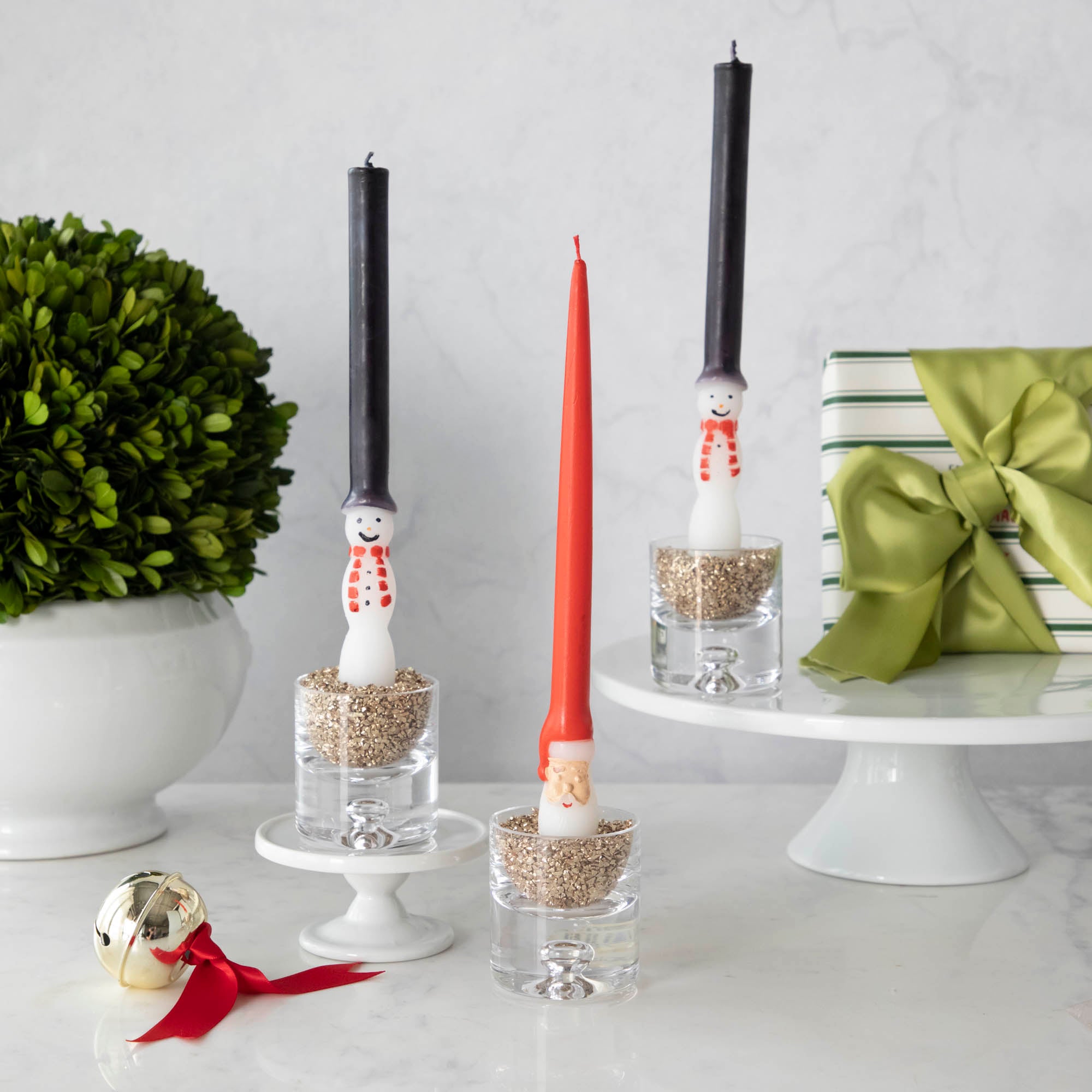 Santa and snowman candles on a white table.