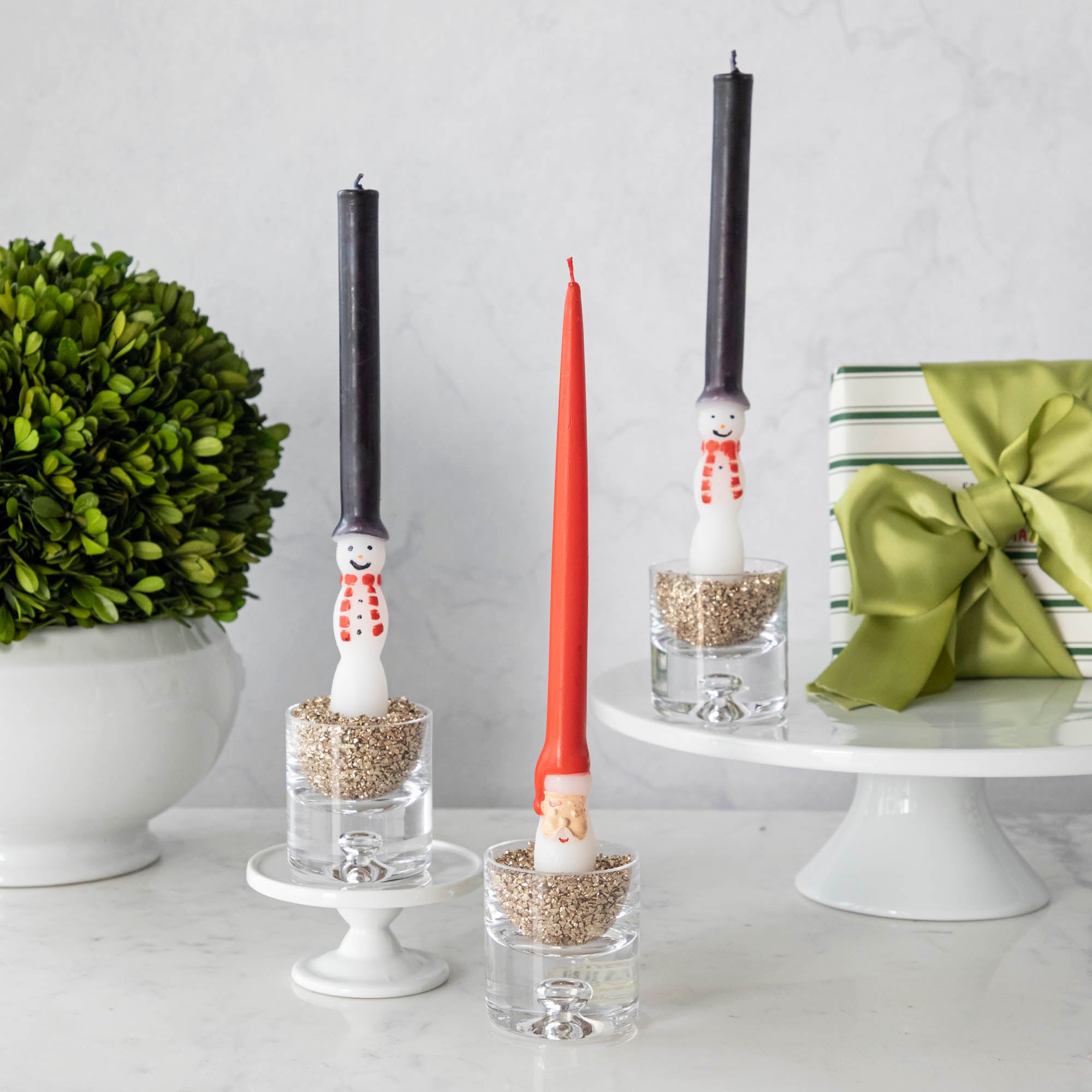 Snowman and Santa candles on a white table.