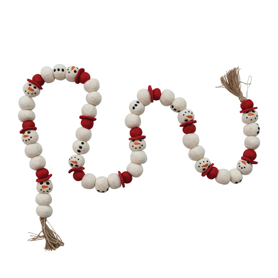 Decorative garland with snowman faces in red hats and jute tassels on a white background.