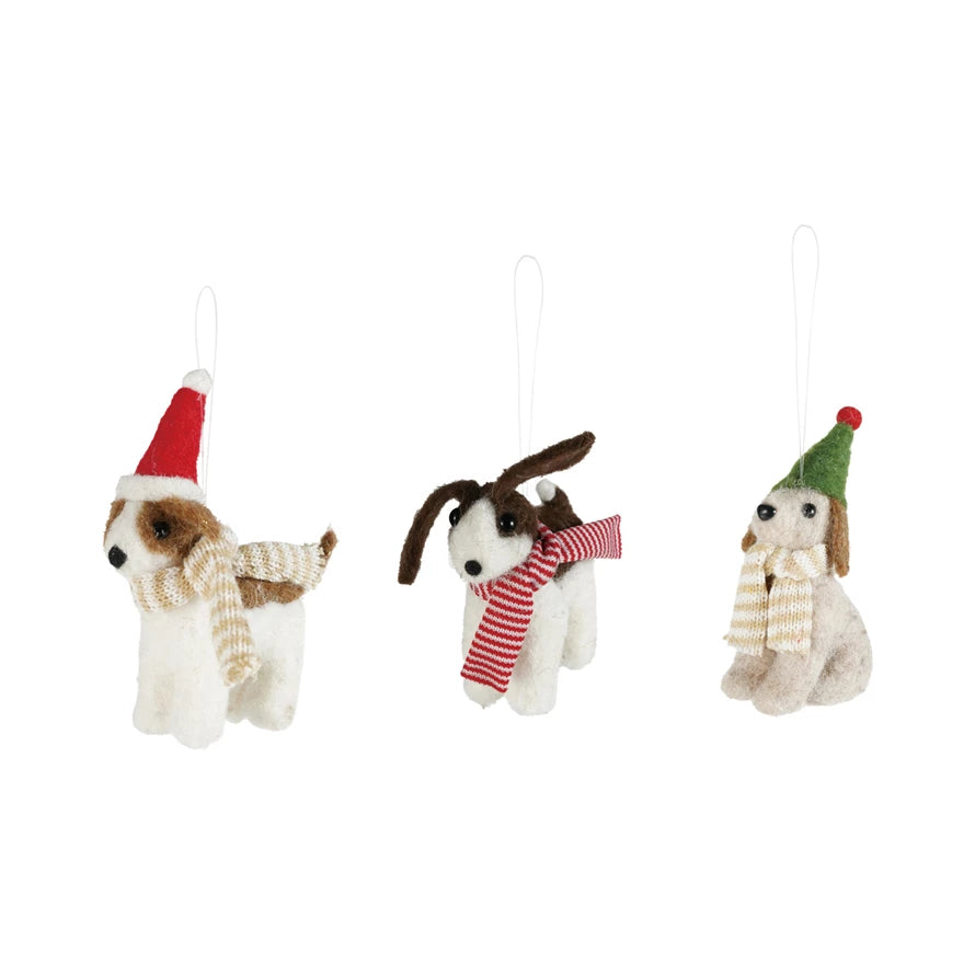 Three dog-shaped Christmas ornaments with scarves and hats on a white background.