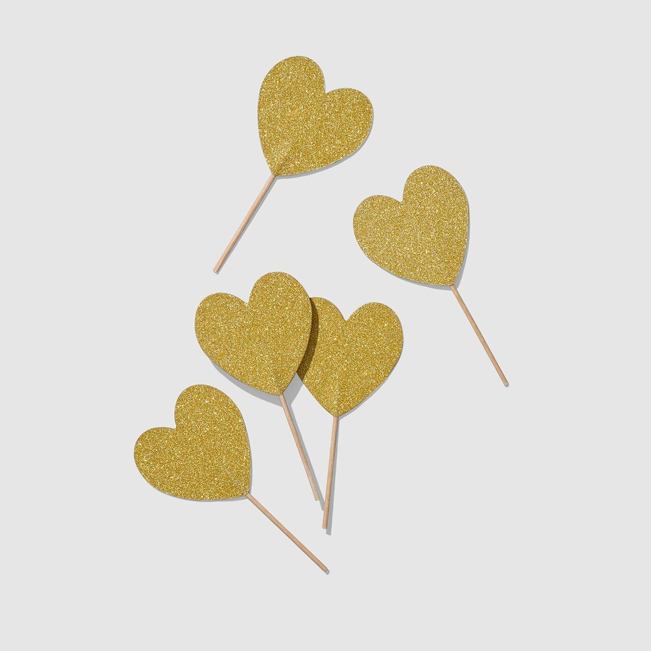 Gold and sparkly heart shaped toppers on a white surface.
