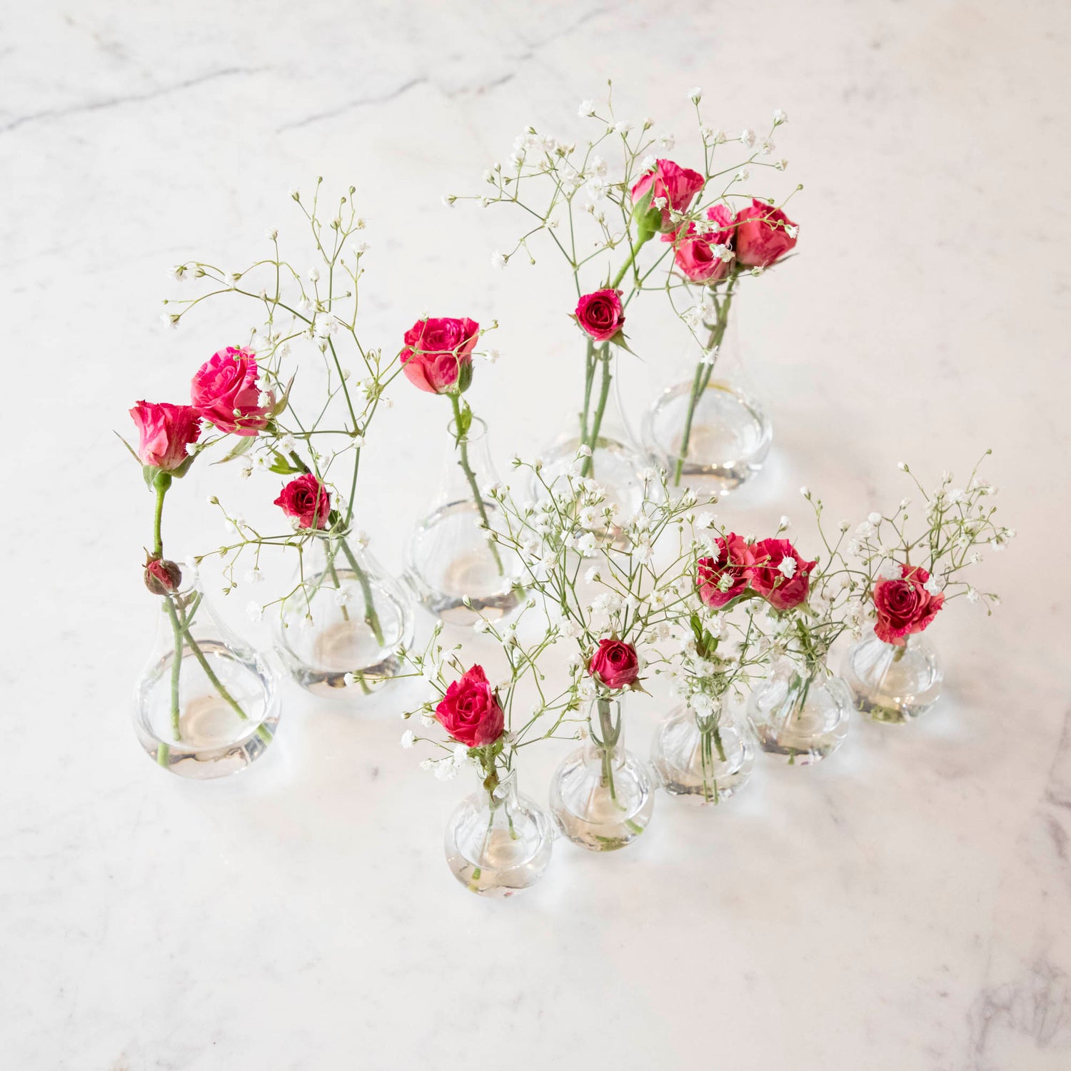 Five Quintet Glass Vases of varying shapes holding floral cuttings of pink roses and baby&