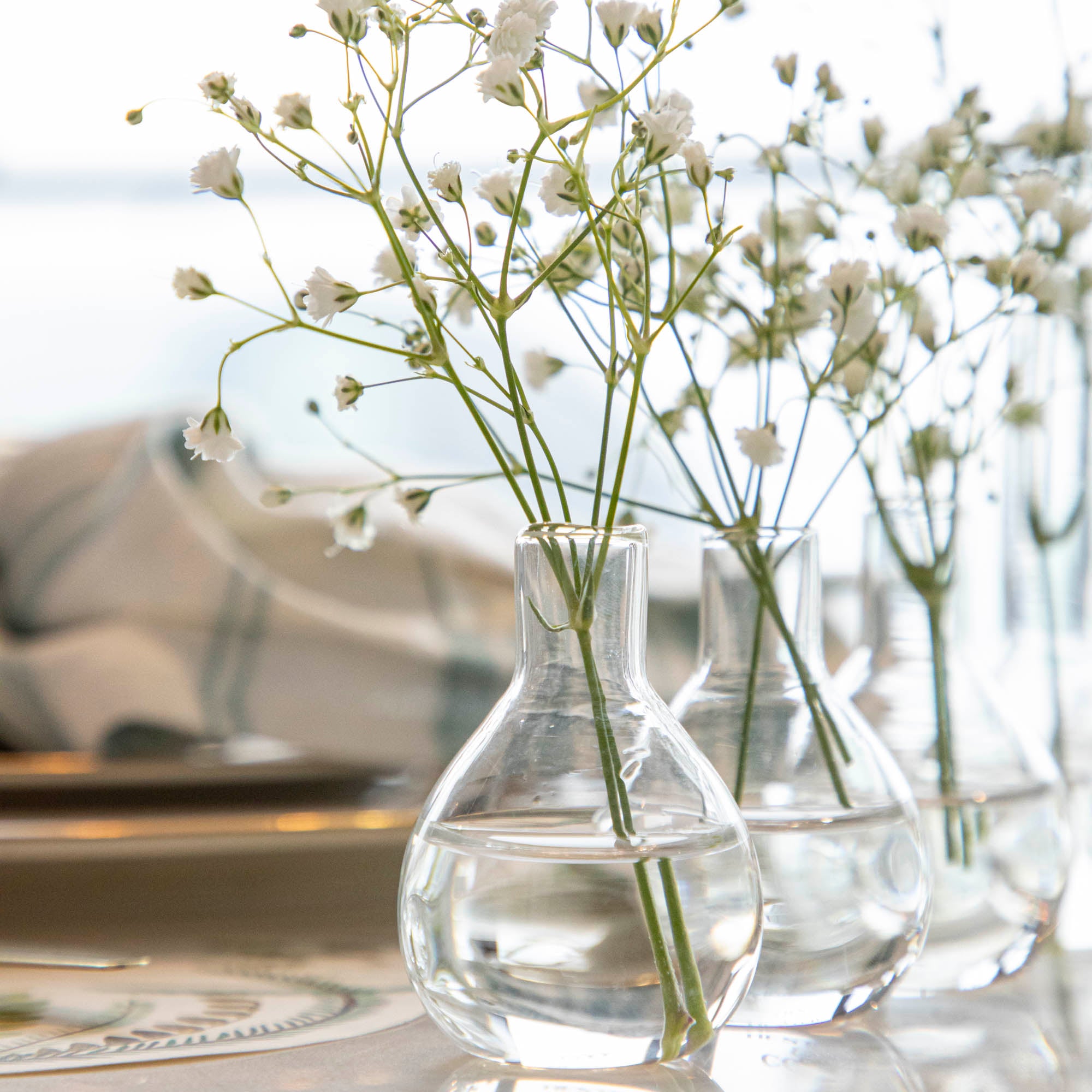Five Quintet Glass Vases of varying shapes holding floral cuttings of pink roses and baby&