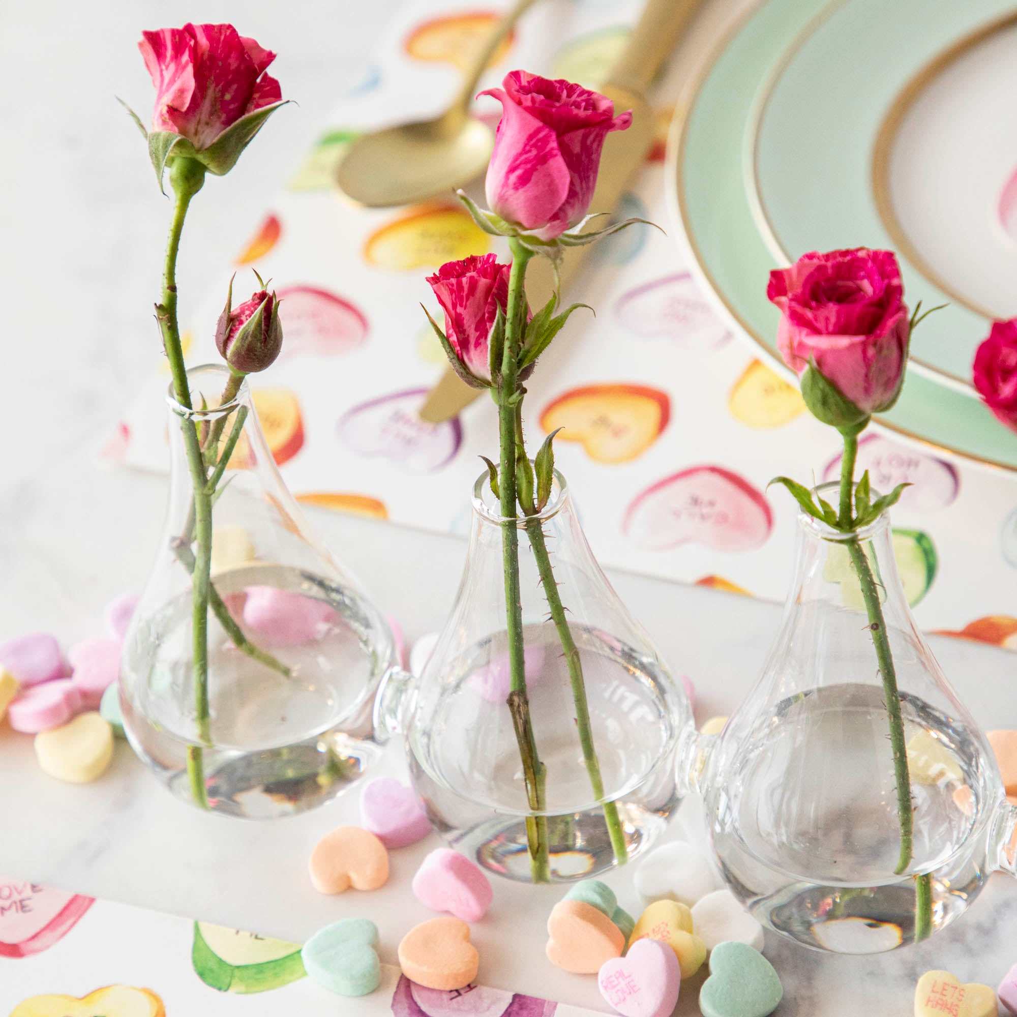 Five Quintet Glass Vases of varying shapes holding floral cuttings of pink roses and baby&
