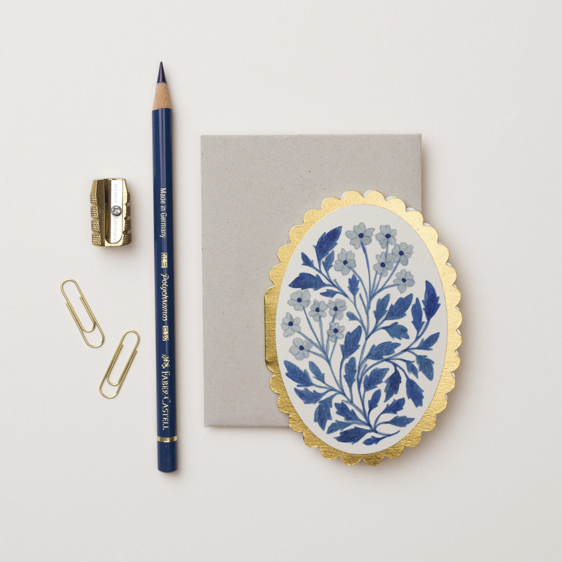 Flat lay of stationery including a pencil, sharpener, paper clips, and a notebook with a floral design alongside Wanderlust Paper Co mini greeting cards on a white background.
