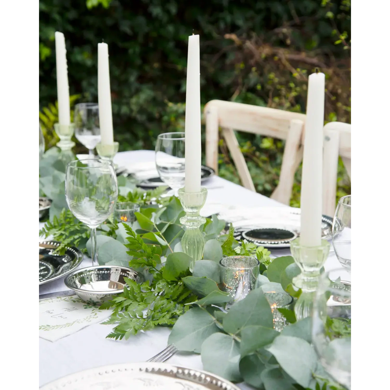 Dinner table set with green pressed glass taper candle holders on it.