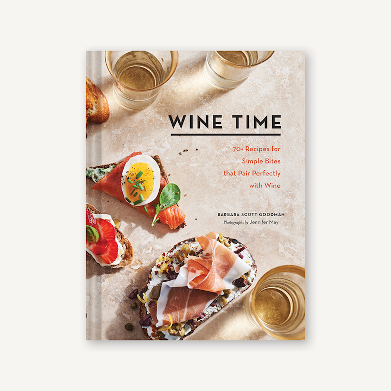 A cookbook titled "Wine Time" by Chronicle Books with recipes for simple bites that pair well with wine pairings, displayed alongside two stemless wine glasses and appetizers.
