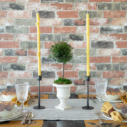 A Stick Candles set and a group of candles on top of a textured brick wall.