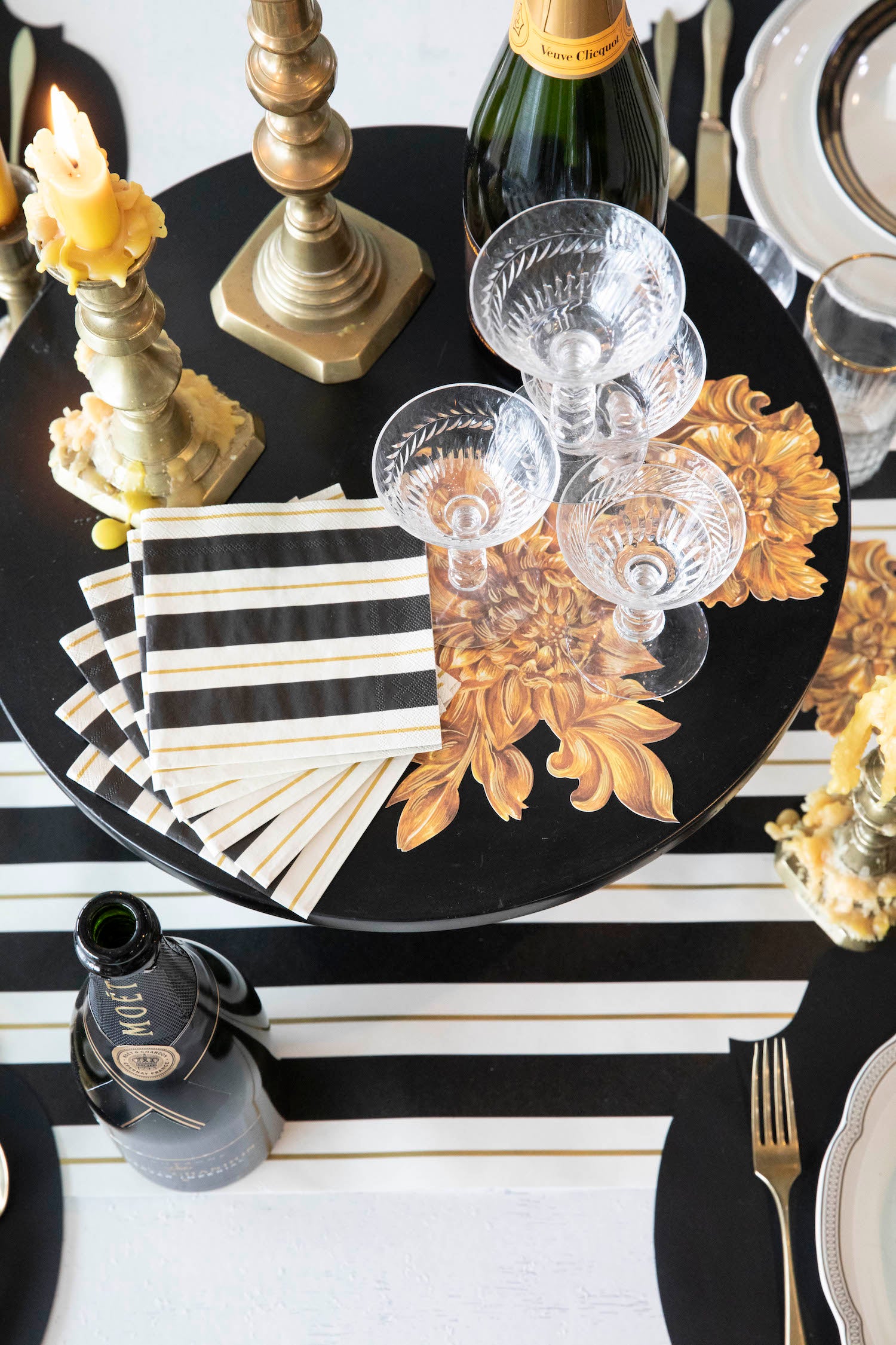 A stack of Black & Gold Awning Stripe Cocktail Napkins fanned out on an elegant tablescape.