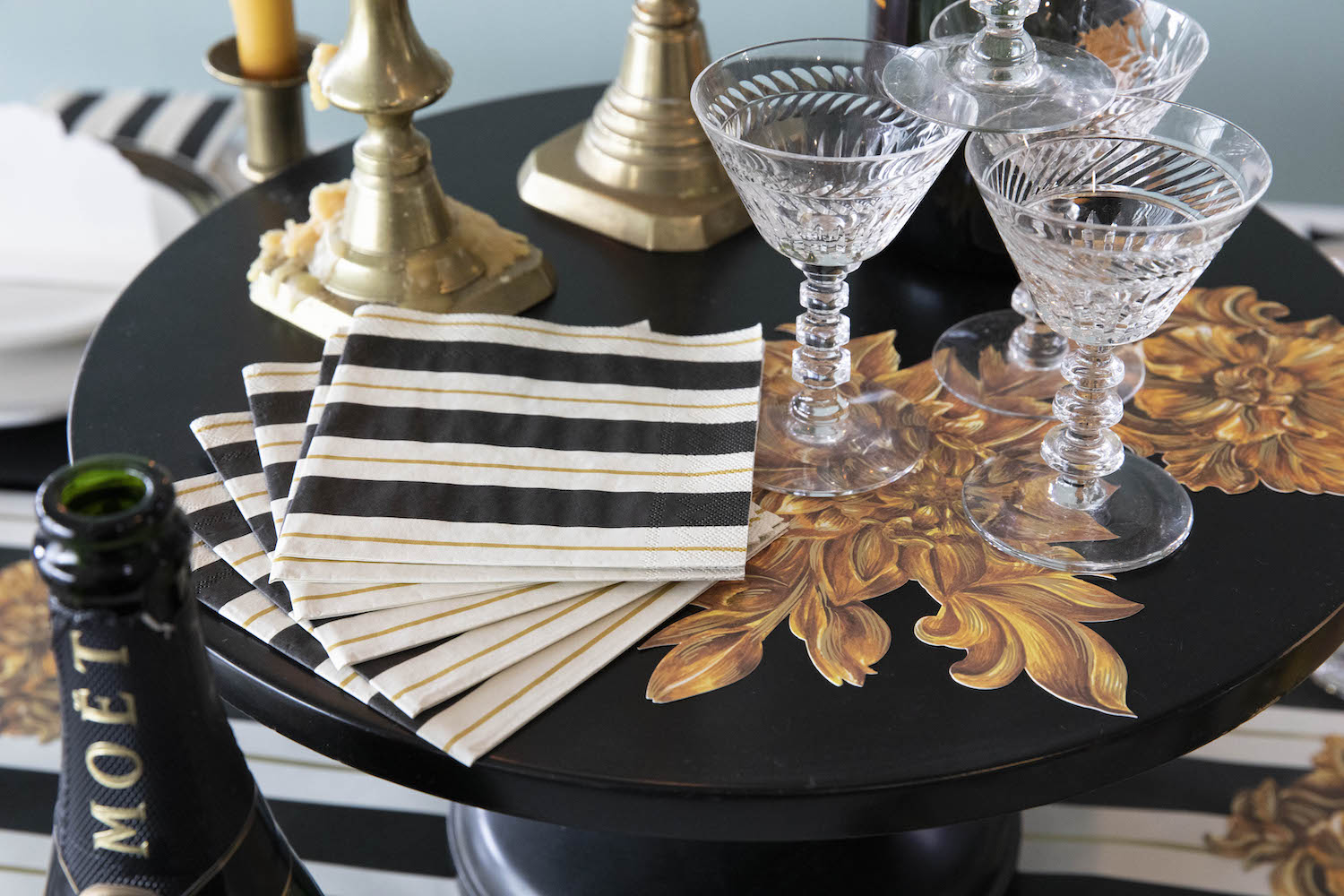 A stack of Black &amp; Gold Awning Stripe Cocktail Napkins fanned out on an elegant tablescape.
