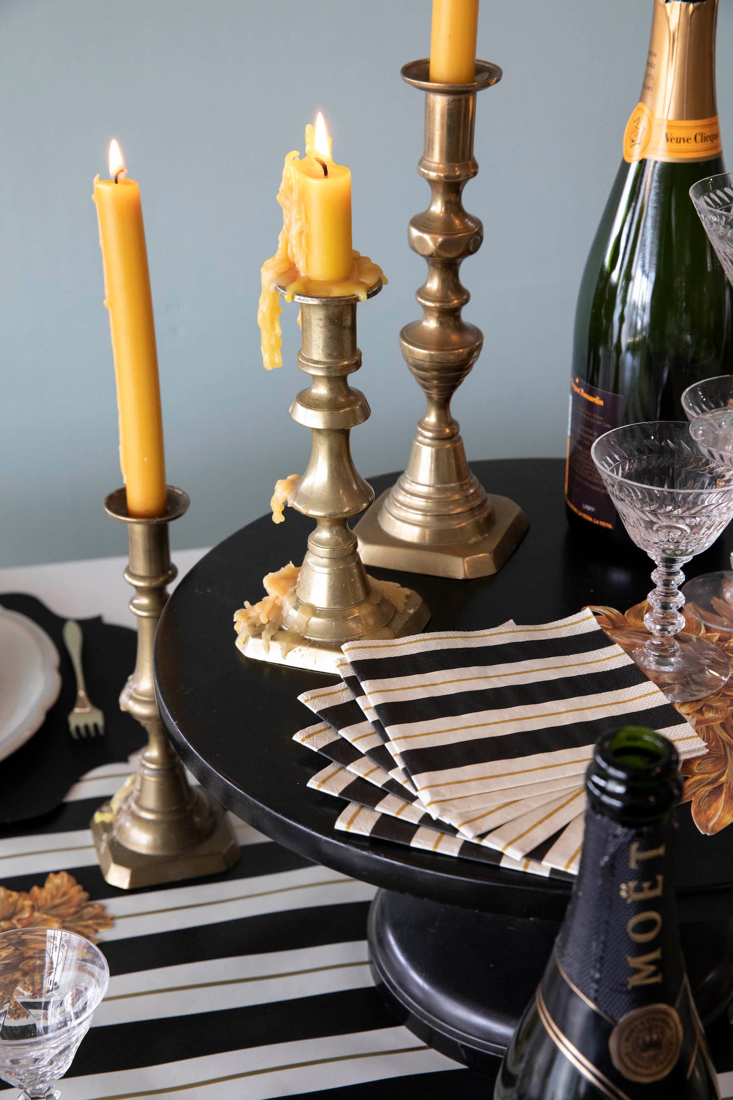A stack of Black &amp; Gold Awning Stripe Cocktail Napkins fanned out on an elegant tablescape.