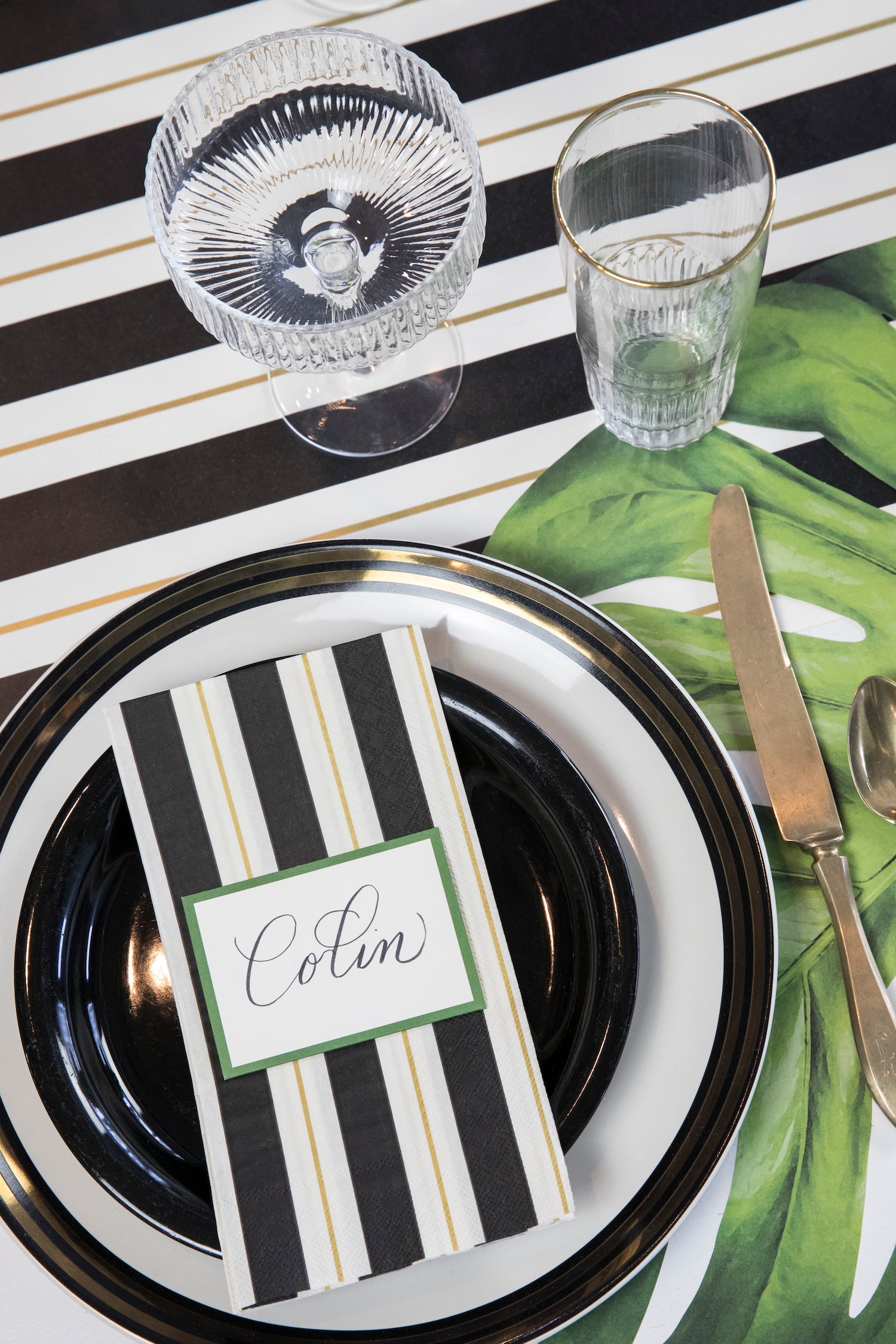 An elegant place setting with a Black & Gold Awning Stripe Guest Napkin on the plate.