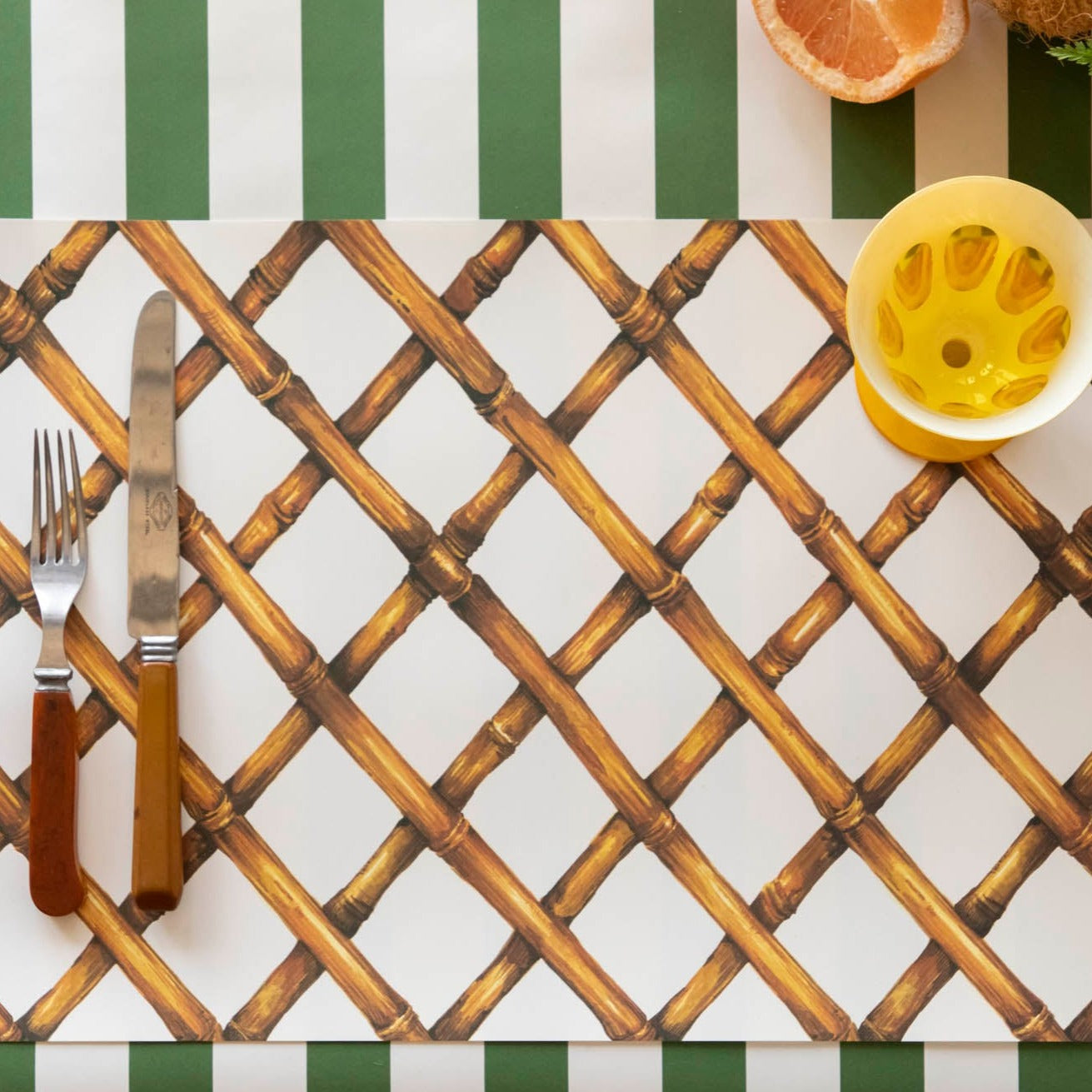 A Bamboo Lattice paper placemat with knife, fork and glass set on top of it.