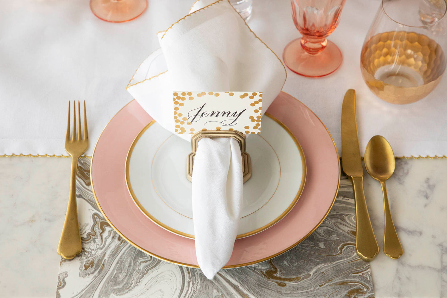 A Brass Napkin Ring with Place Card Holder on the plate of an elegant place setting, from above.