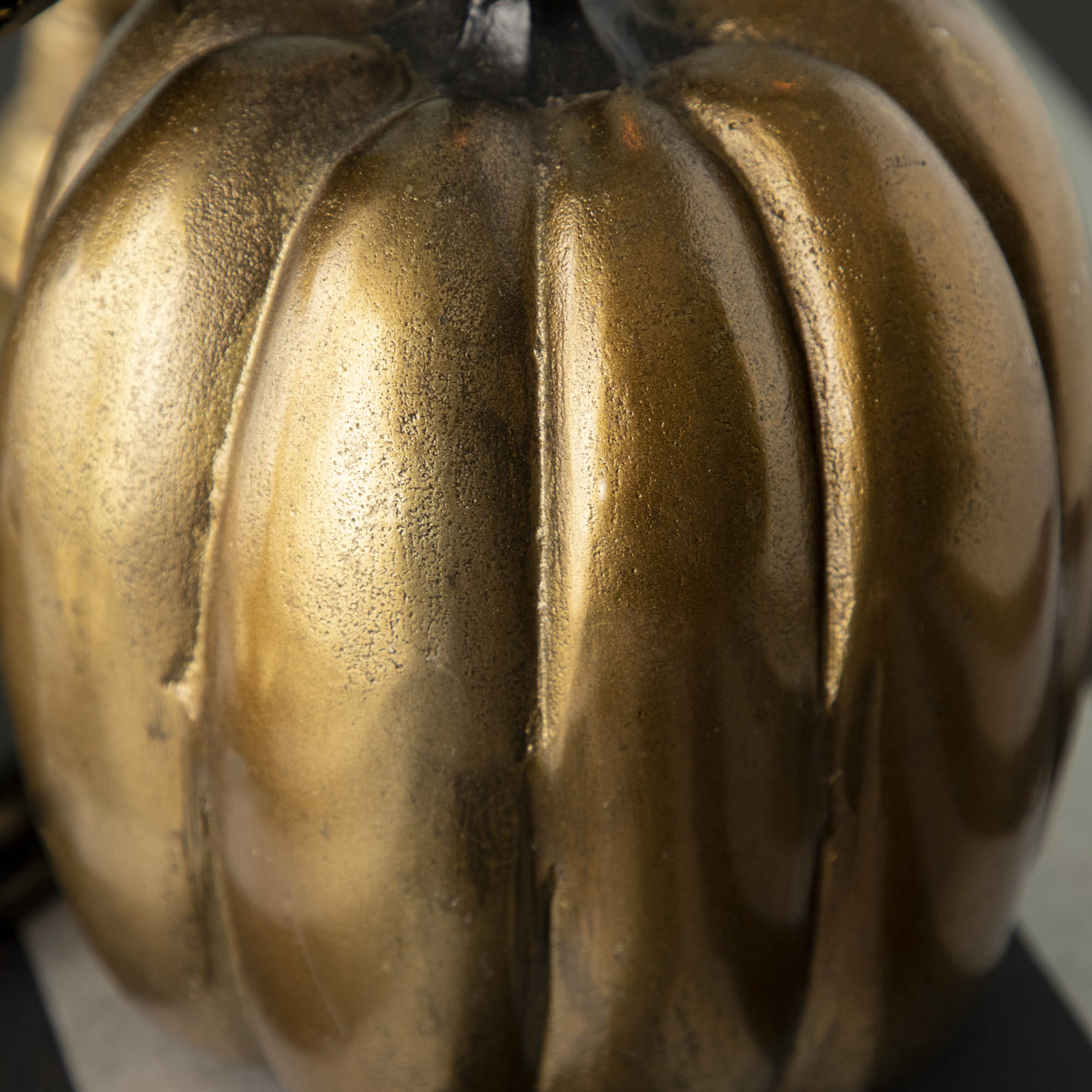 Three handmade Accent Decor brass pumpkins on a wooden table.