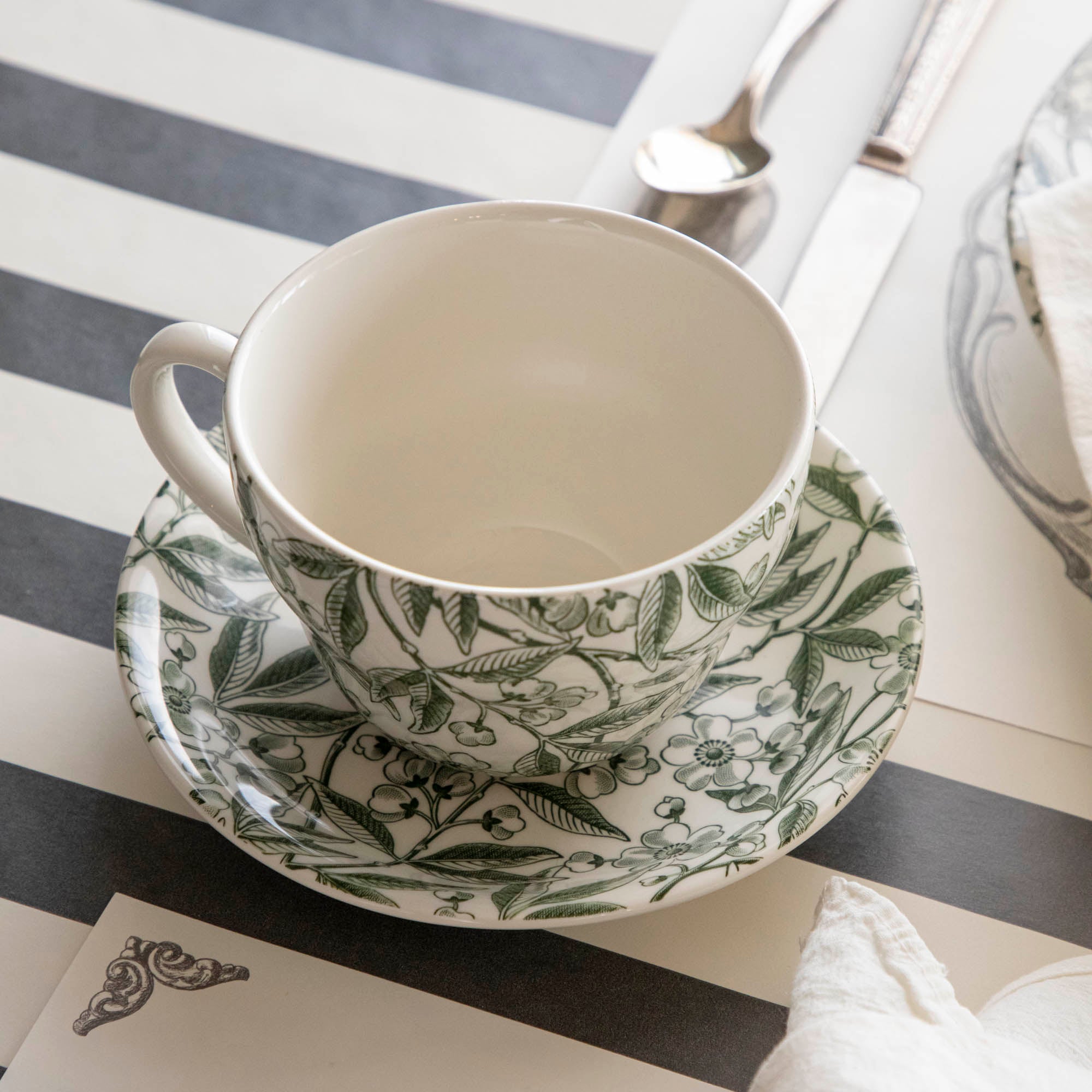 Burleigh Green Prunus cup and saucer behind a place setting on the Black Classic Stripe Runner.
