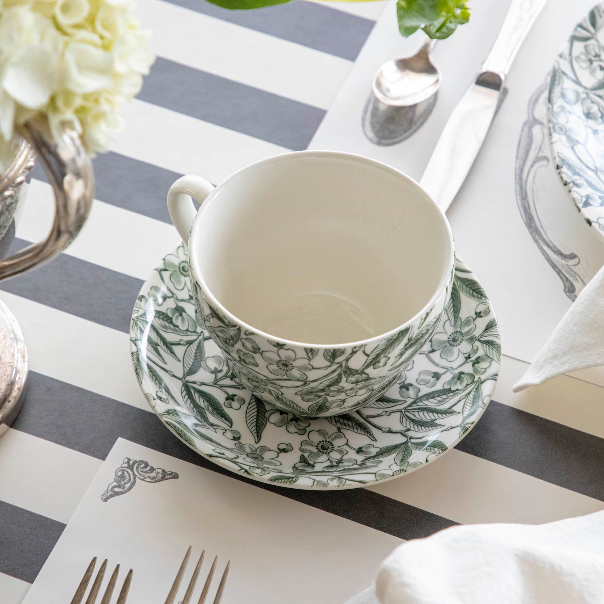 Elegant table setting with Burleigh Green Prunus Dinnerware plates and green striped tablecloth.