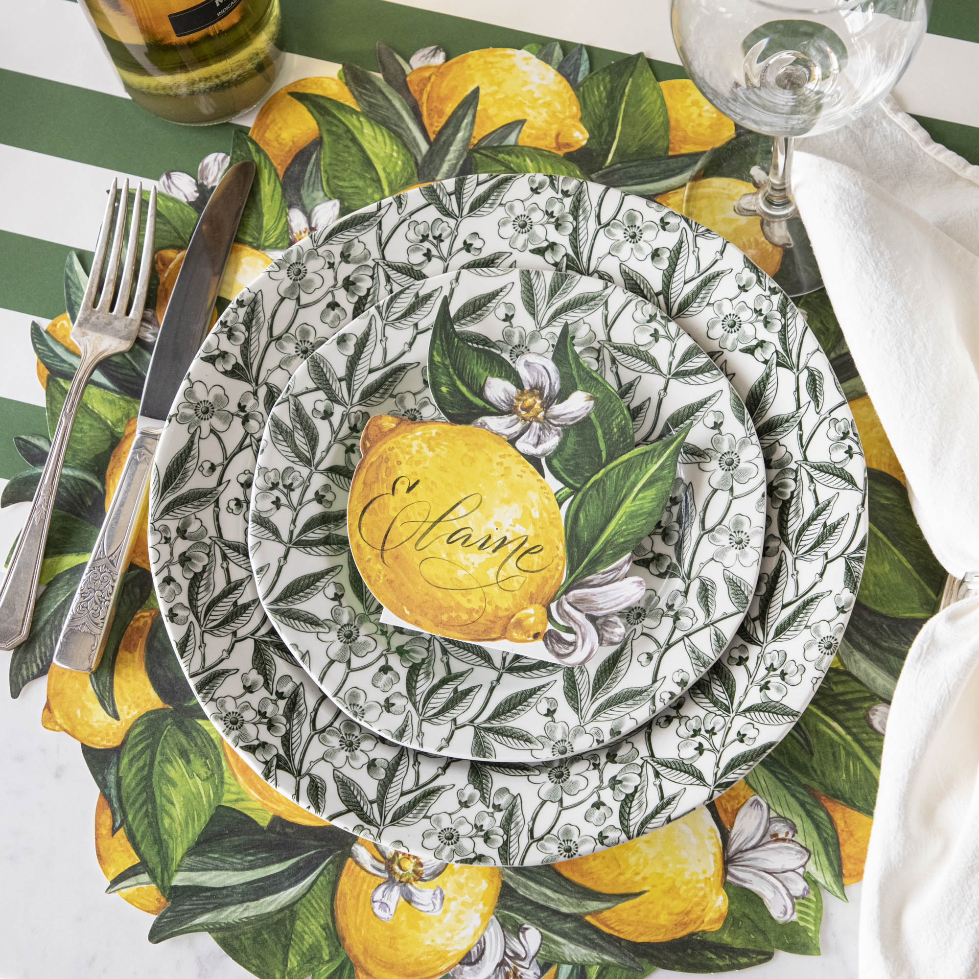 Elegant table setting with Burleigh Green Prunus Dinnerware plates. Die-cut Lemon Wreath Placemat and vintage silverware on the Dark Green Classic Stripe Runner.