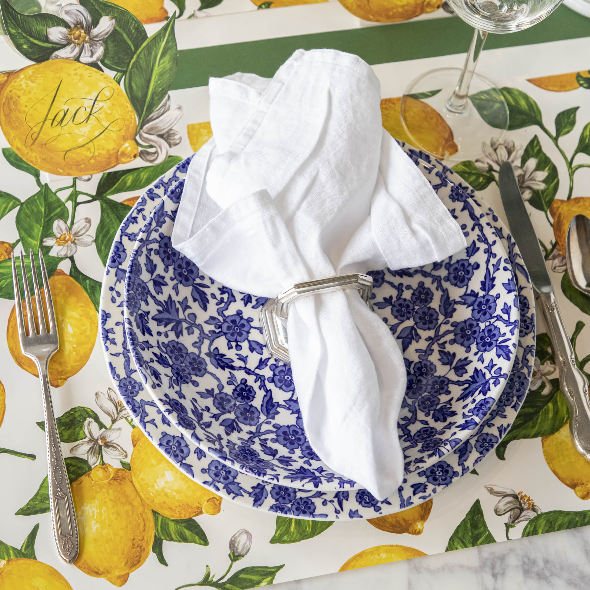 A Burleigh Blue Arden dinnerware plate on a wicker placemat with a folded napkin and a fork to the side, also noted as dishwasher safe.
