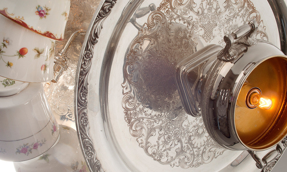 The top view of the Tea Party Chandelier showing a bulb inside of a teapot, attached to a vintage silver-plate tray and hanging teacups.