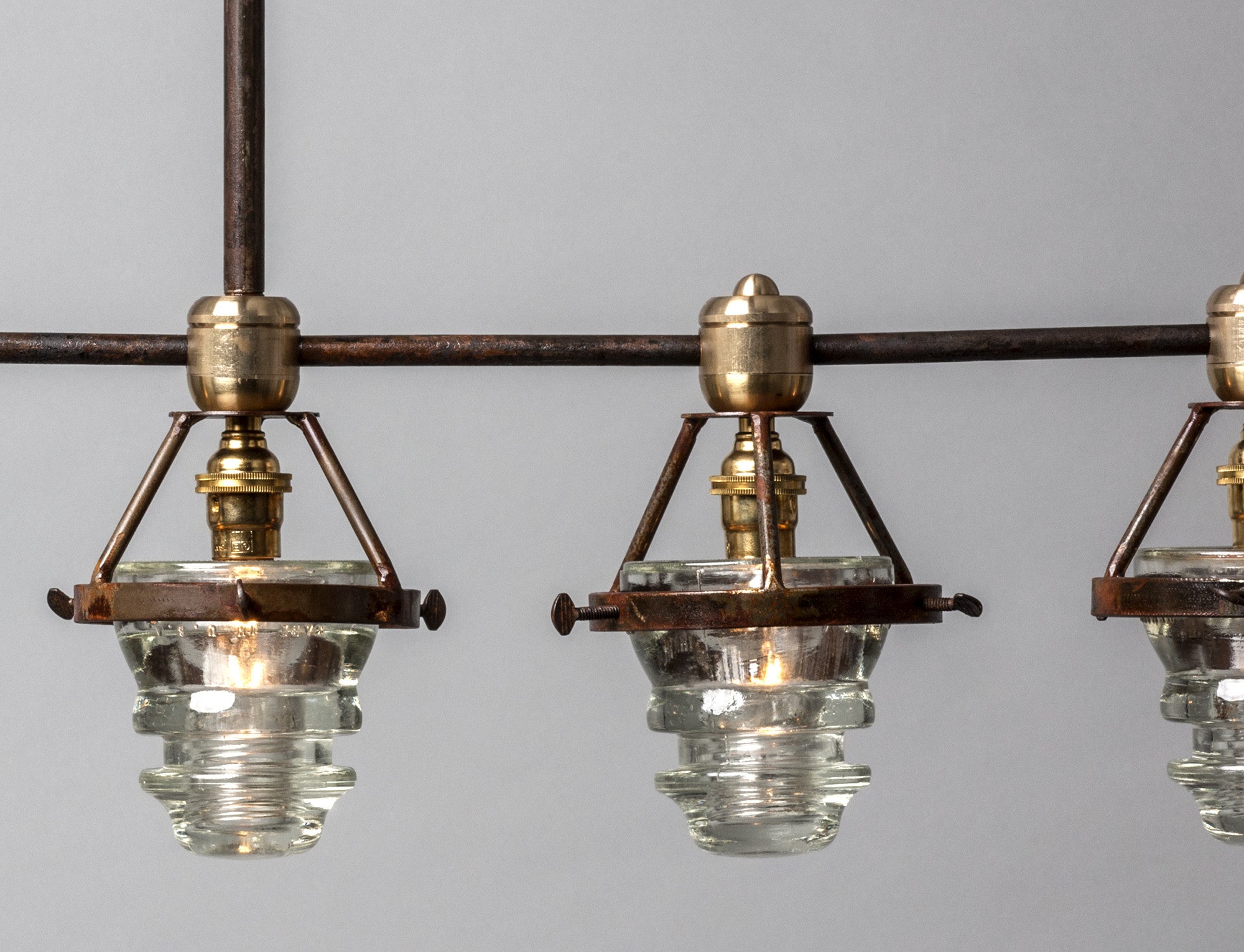 A Telegraph Pendant Lighting with four glass shades and antique insulators hanging from a brass frame. (Brand Name: Hester &amp; Cook)