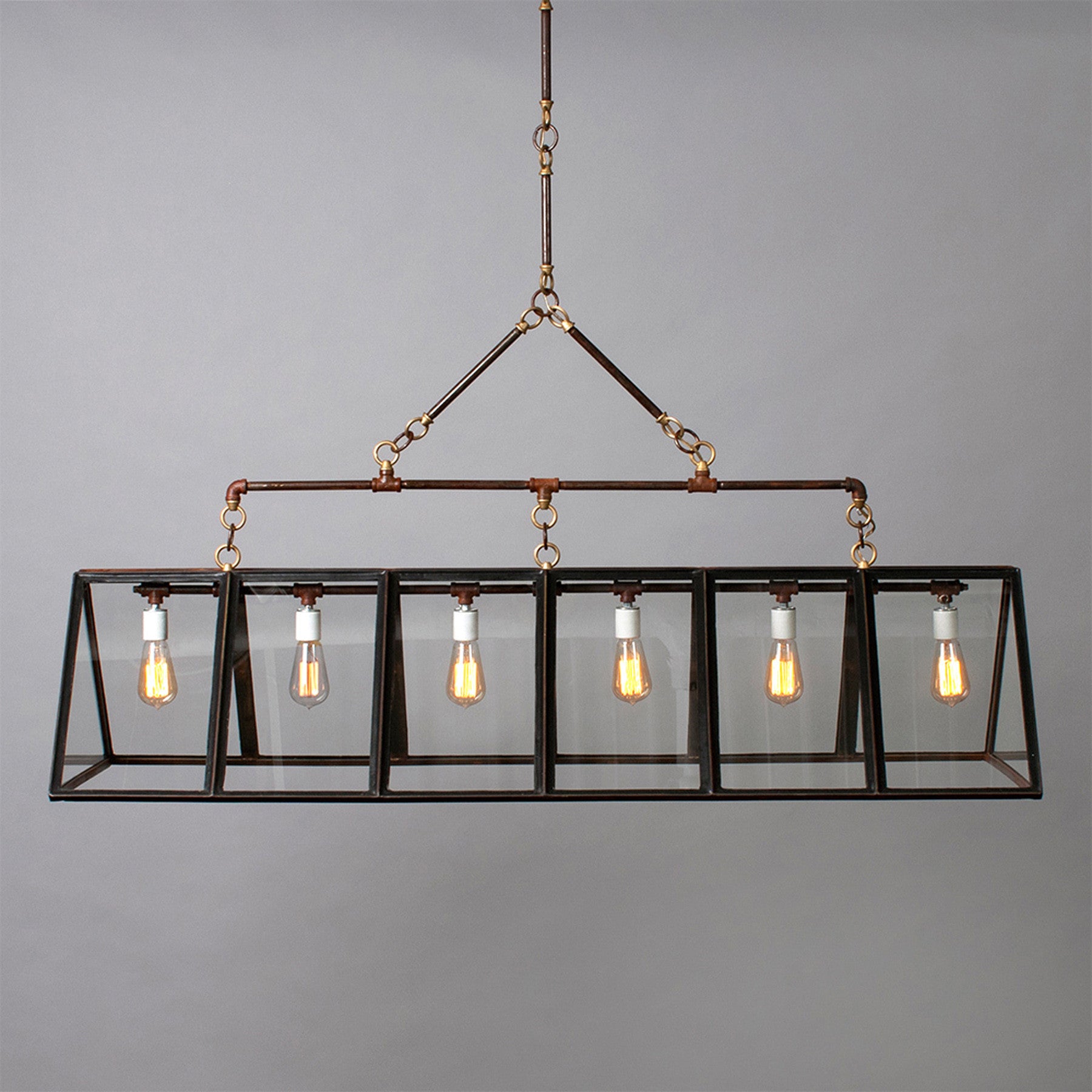 Rectangular metal chandelier with a glazed finish and six exposed light bulbs in a glass and metal box frame, hanging against a plain gray background.
