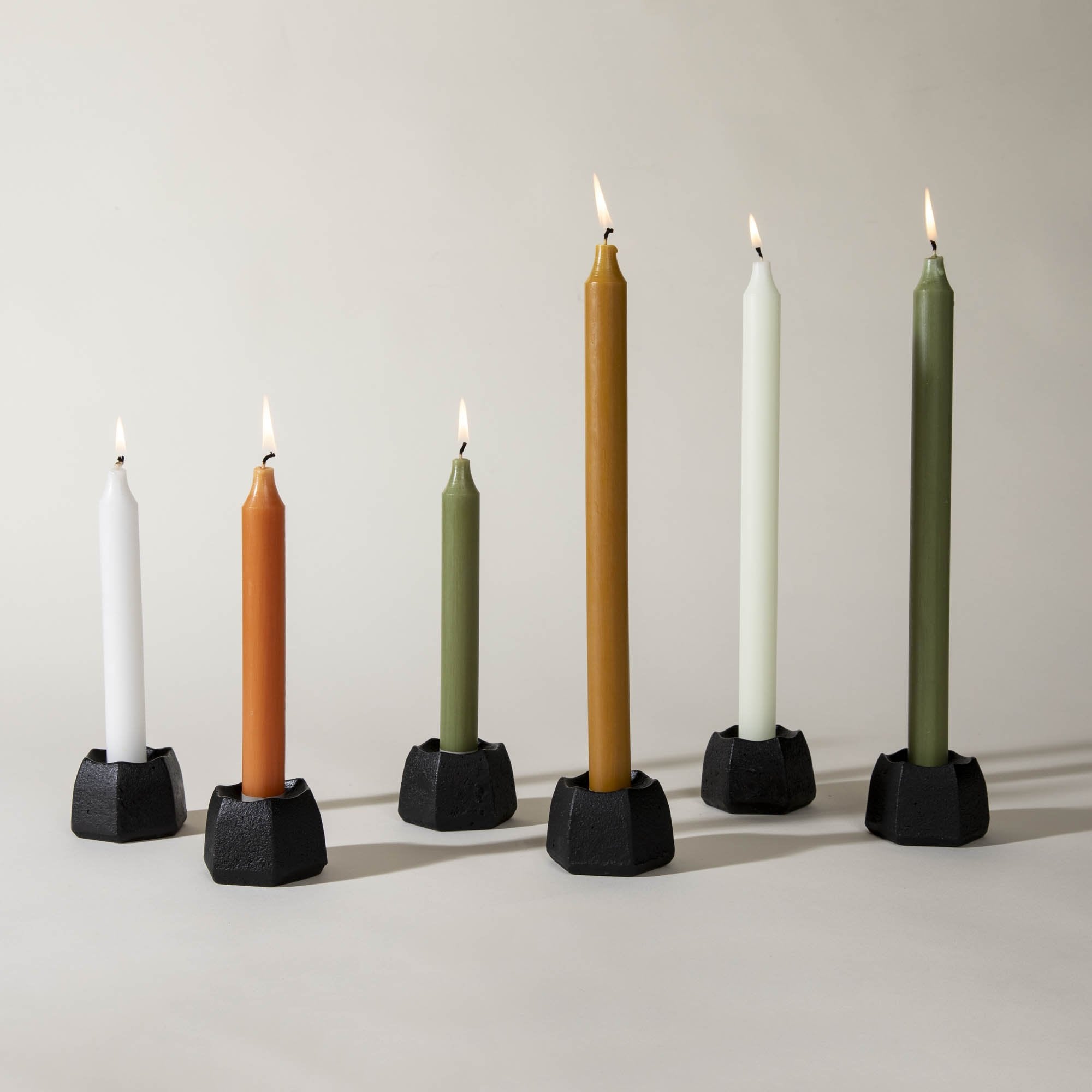 Five Northern Lights Caramel 12" Taper Candles are lined up in a row on a white surface.