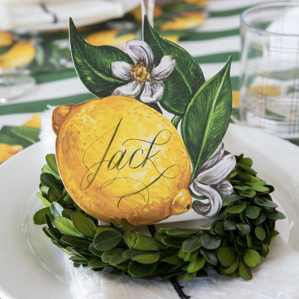 Close-up of an elegant place setting featuring a Lemon Place Card labeled &quot;Jack&quot; standing on the plate.