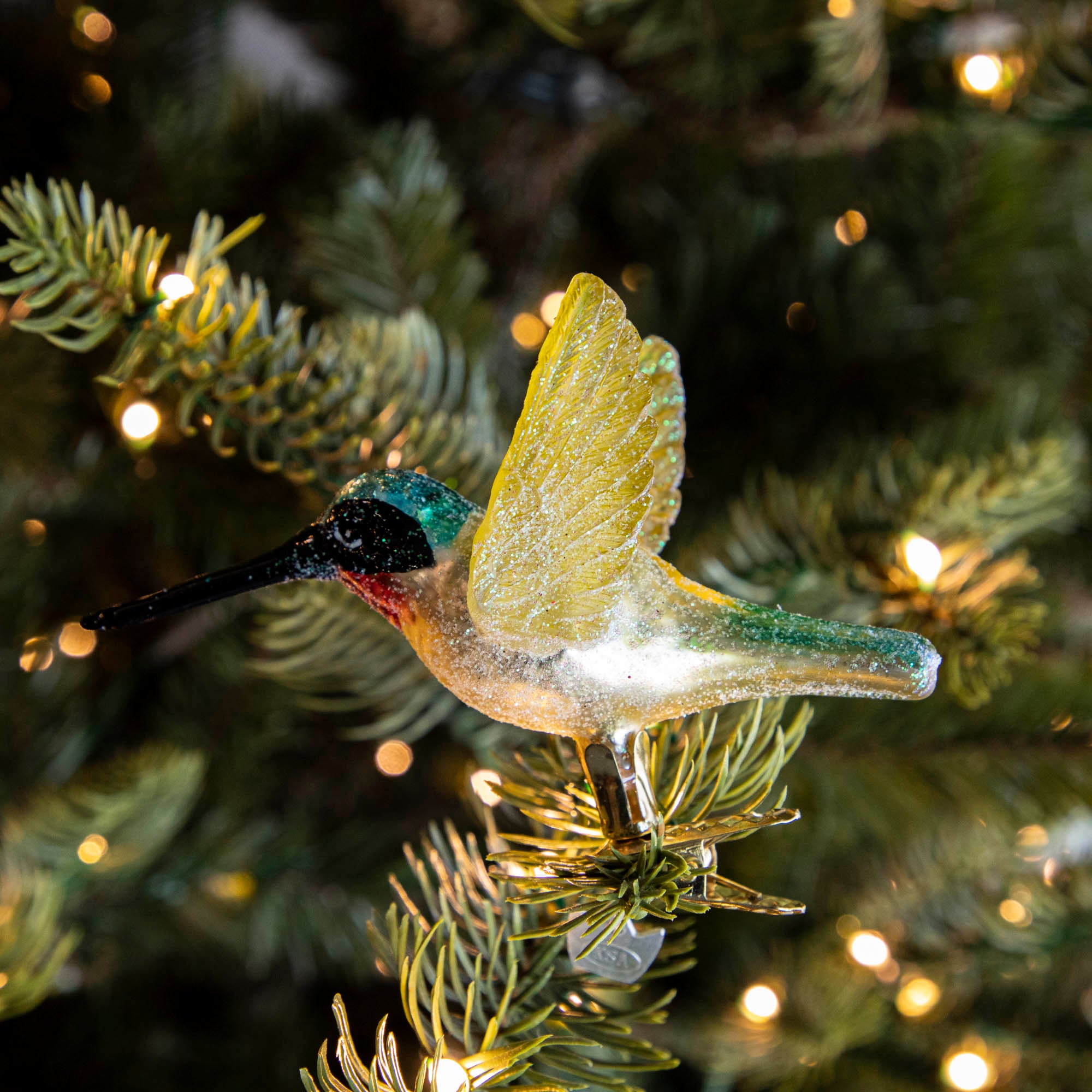 Glass Hummingbird Ornament clipped into a tree.