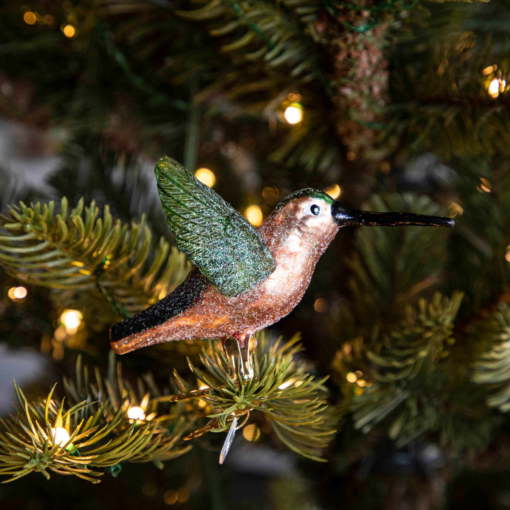 Glass Hummingbird Ornament clipped into a tree.