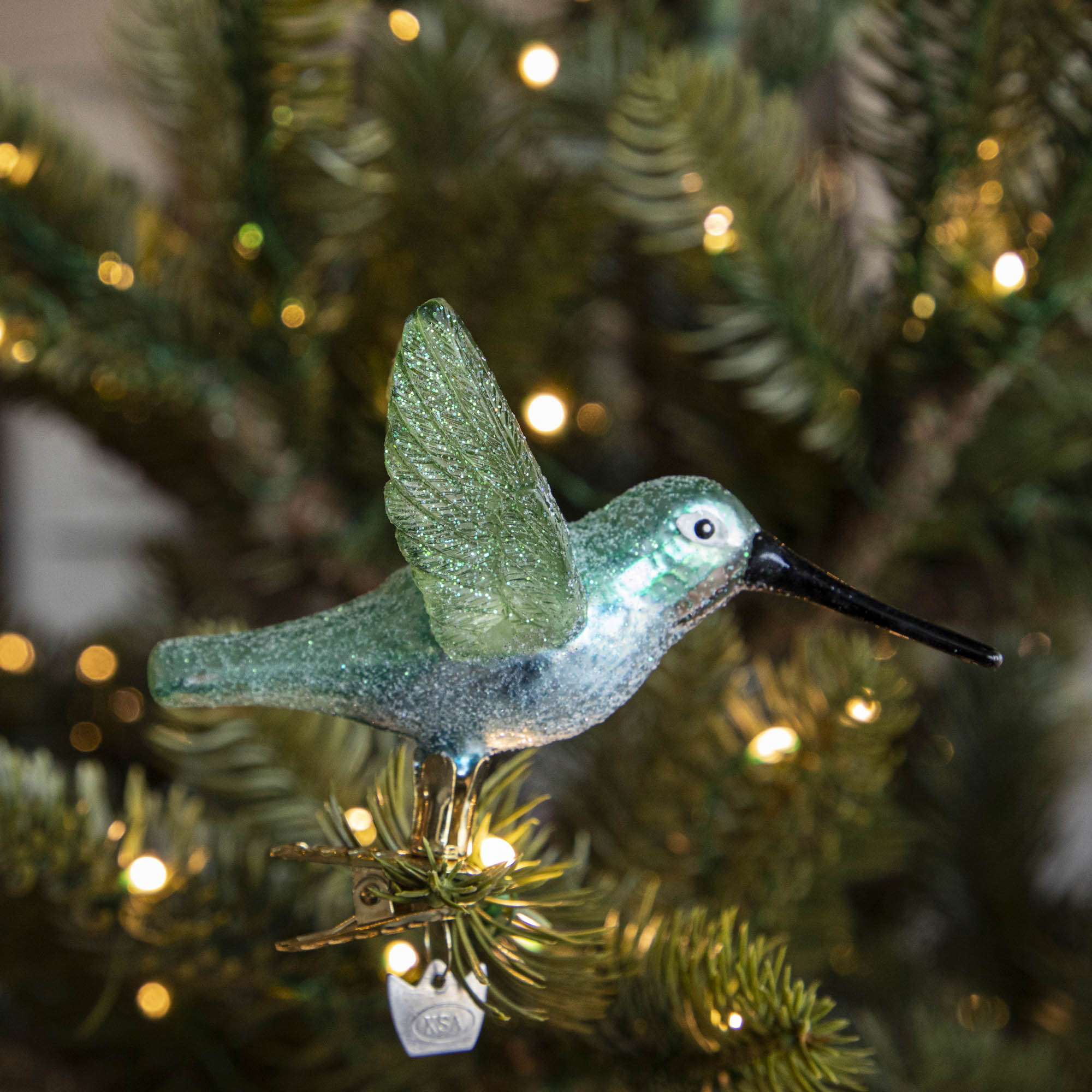 Glass Hummingbird Ornament clipped into a tree.