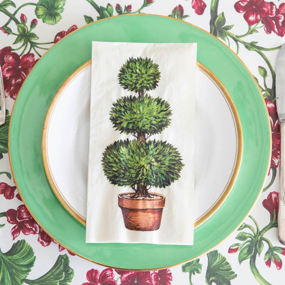 A Topiary Guest Napkin centered on the plate of a garden-themed place setting, from above.