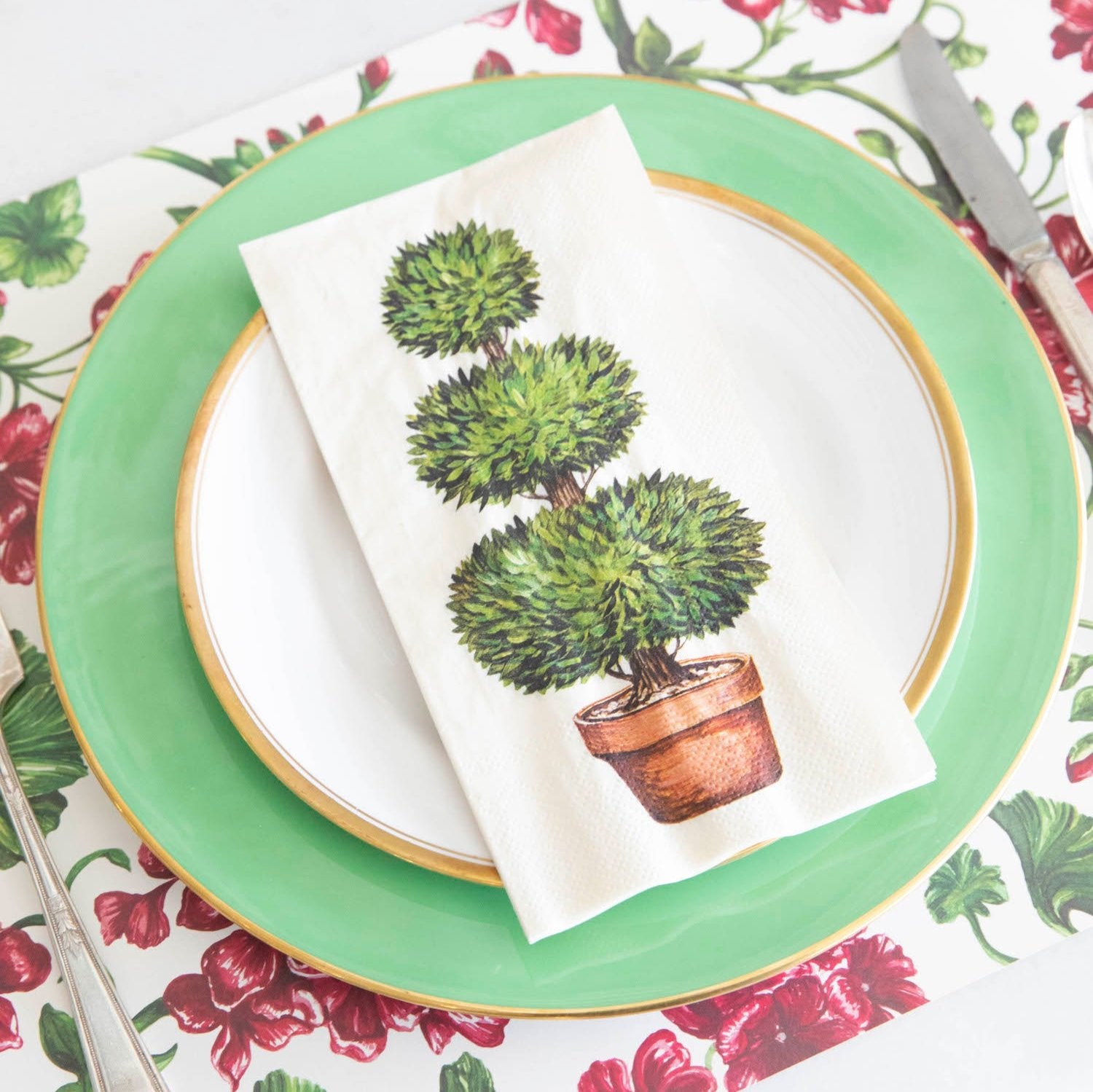 A Topiary Guest Napkin centered on the plate of a garden-themed place setting.