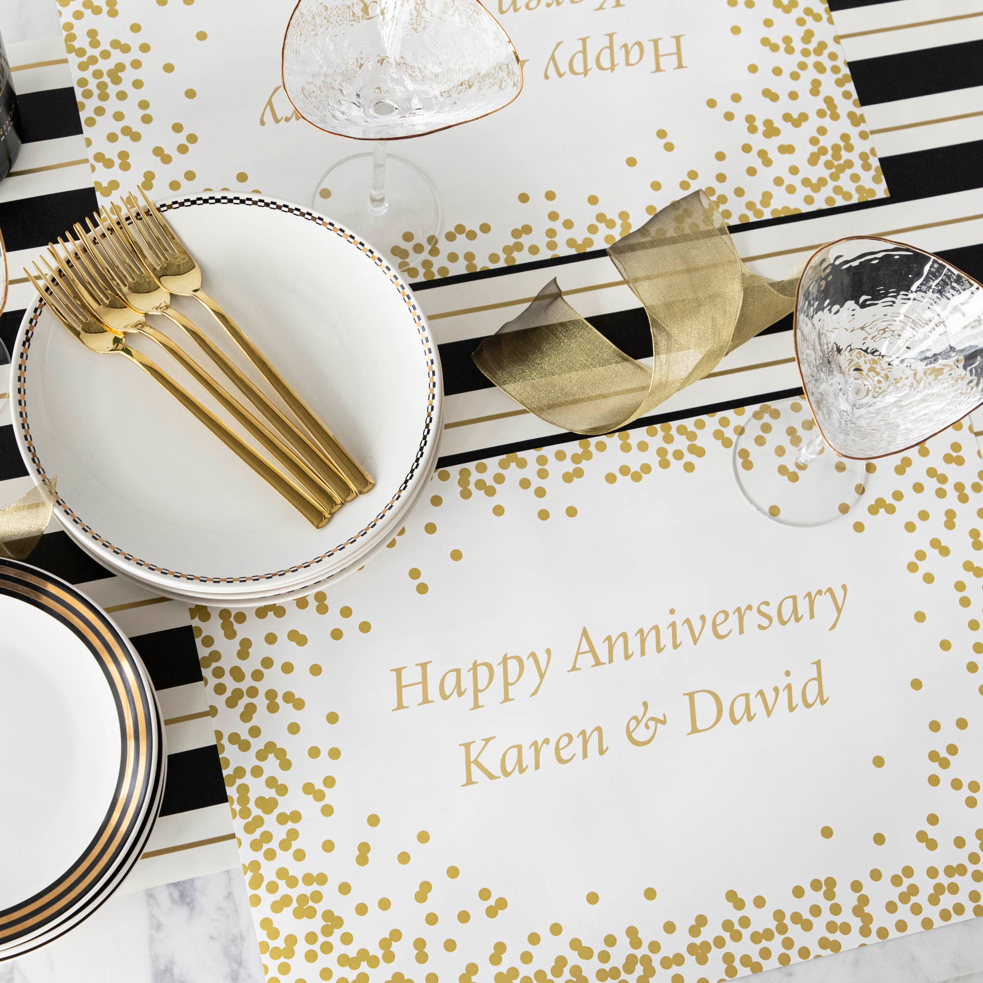 Table setting with Gold Confetti Placemat with personalized message printed in gold color: "Happy Anniversary Karen & David".