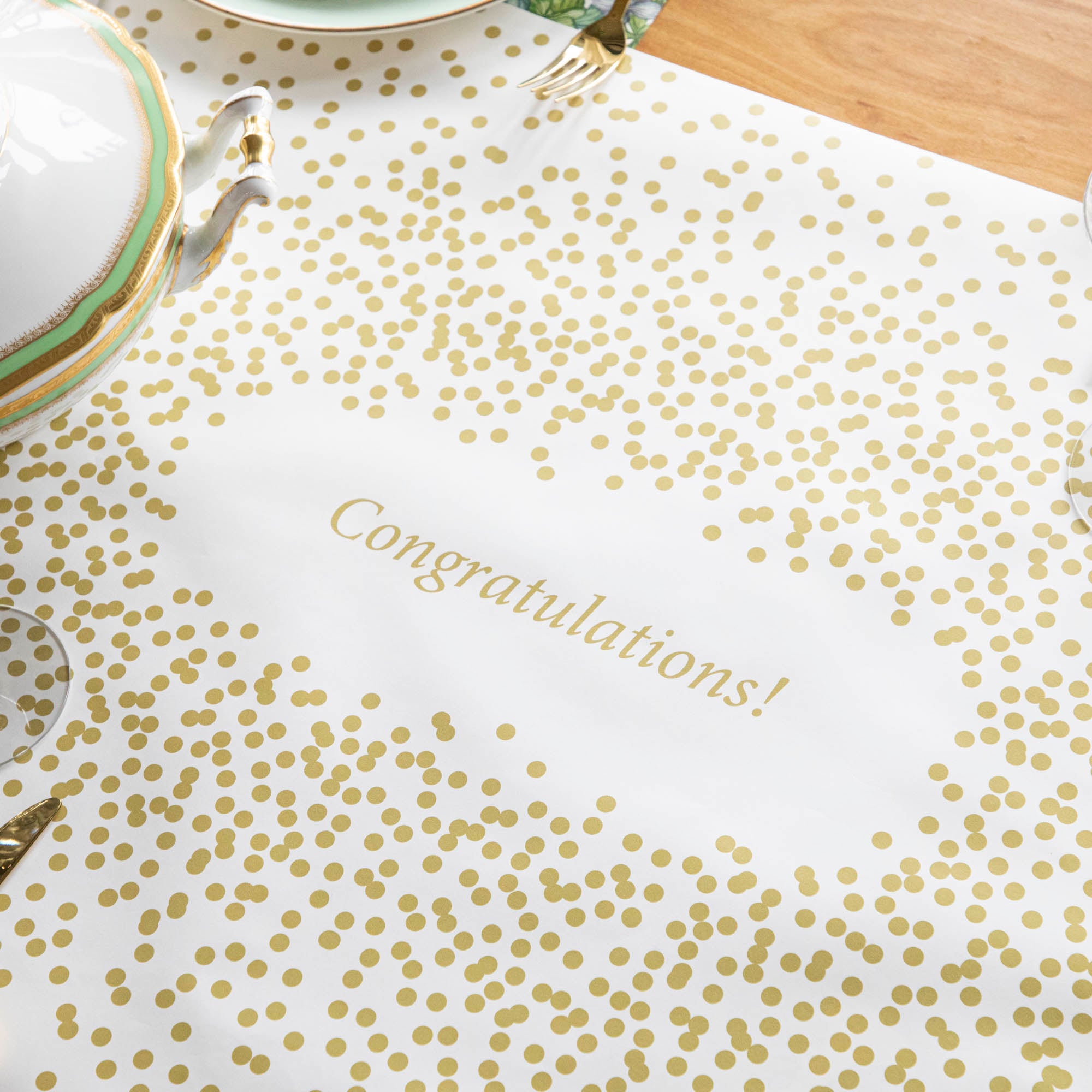 The Gold Confetti Personalized Runner under an elegant table setting, with "Congratulations!" printed in gold in the center.
