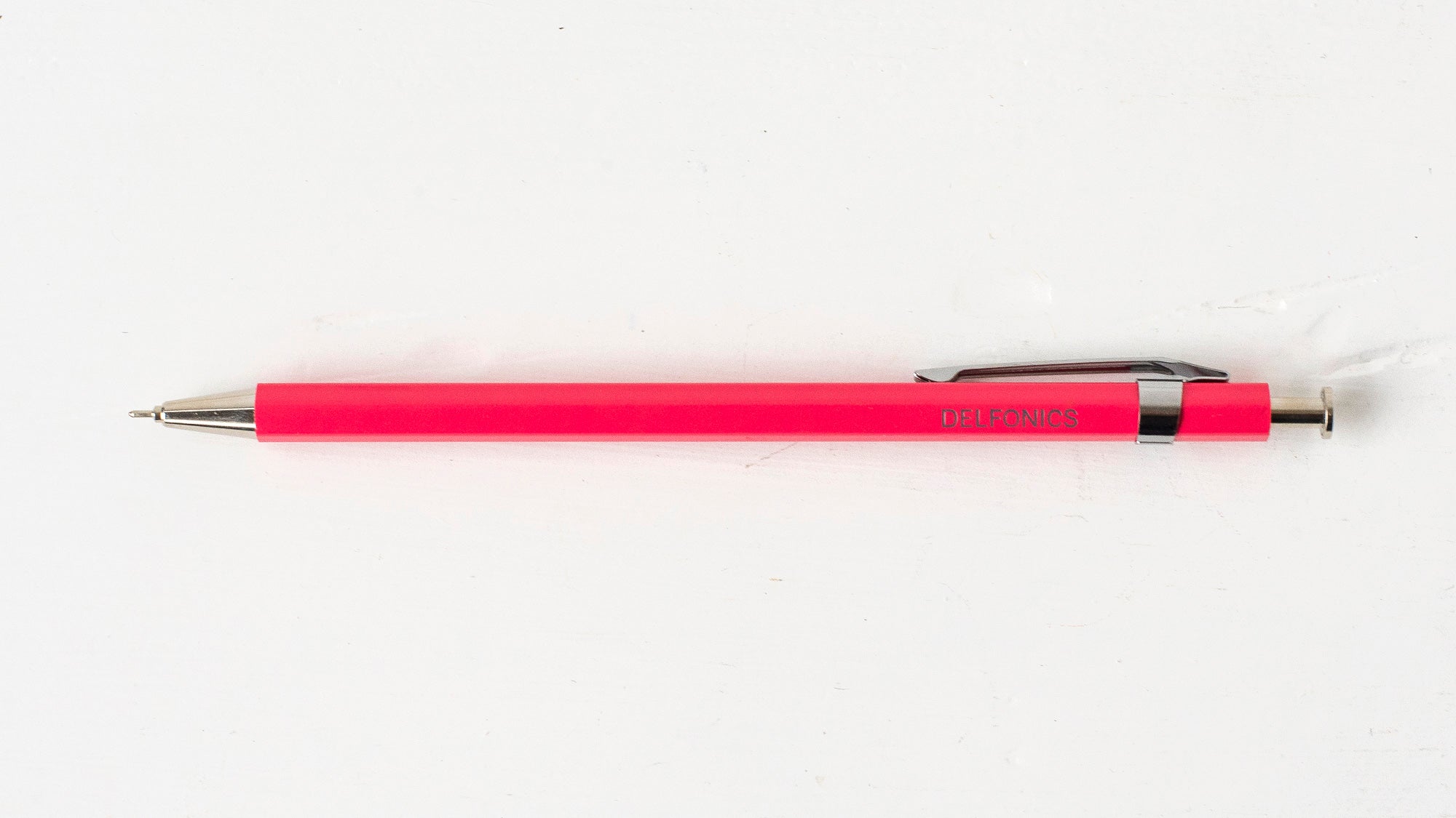 A bright pink wooden ball pen with the brand name &