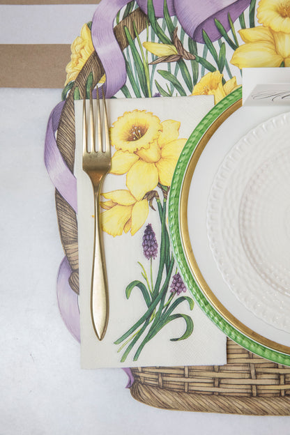 A Daffodil Guest Napkin next to a plate in an elegant springtime place setting, from above.