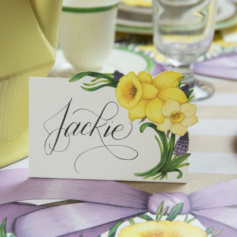 A Hester & Cook Daffodil Place Card reading "Jackie" on an elegant place setting.