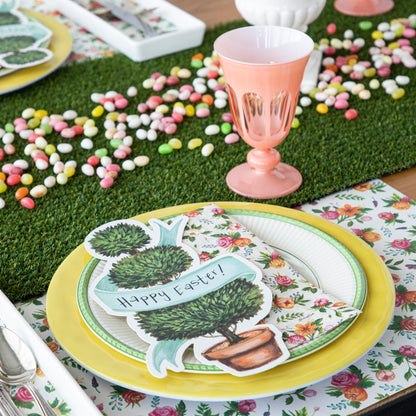 An easter table setting with colorful plates, napkins, and a Talking Tables Artificial Grass Table Runner.