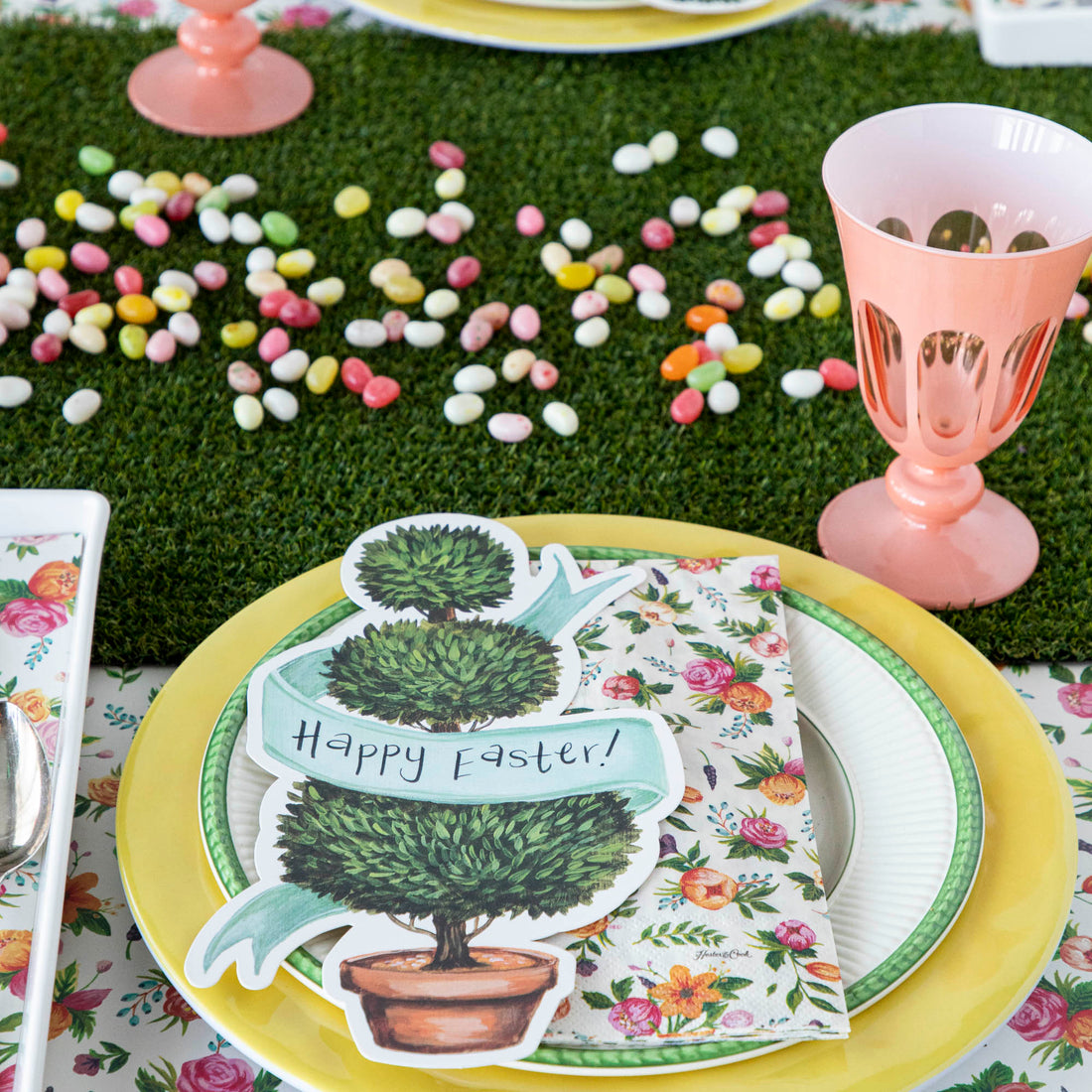 A festive Easter table setting with colorful plates and napkins, adorned with a Talking Tables Artificial Grass Table Runner.