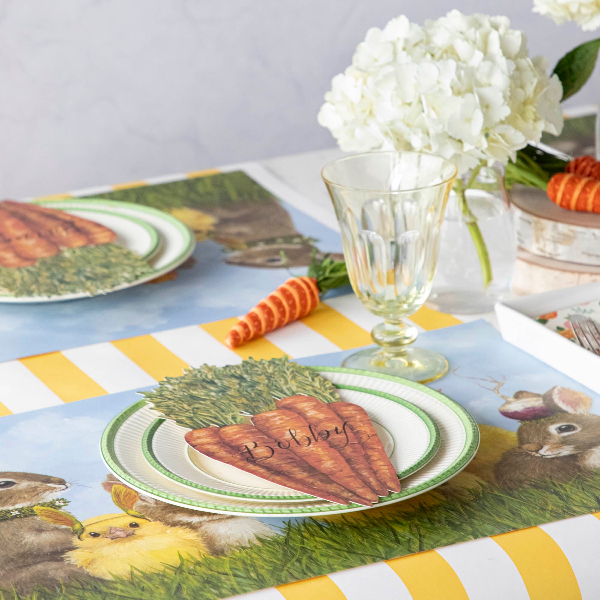 An elegant springtime table setting featuring Carrots Table Accents resting on each plate with names written on them in elegant script.