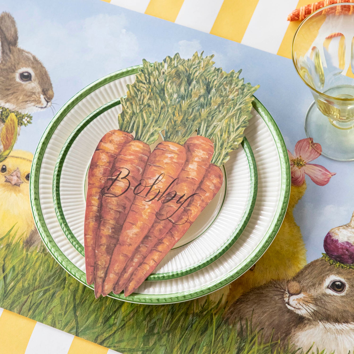 A Carrots Table Accent labeled &quot;Bobby&quot; resting on the plate of a springtime place setting.