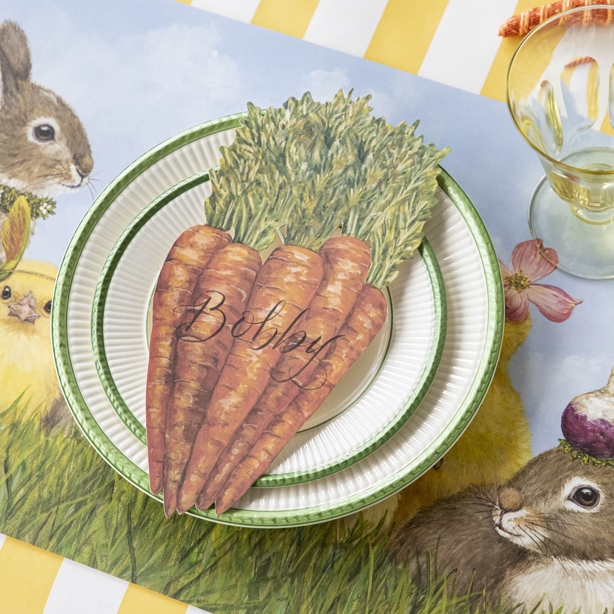 A Carrots Table Accent labeled "Bobby" resting on the plate of a springtime place setting.