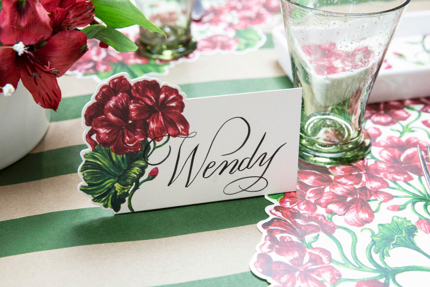 A Geranium Place Card labeled "Wendy" on an elegant floral table setting.