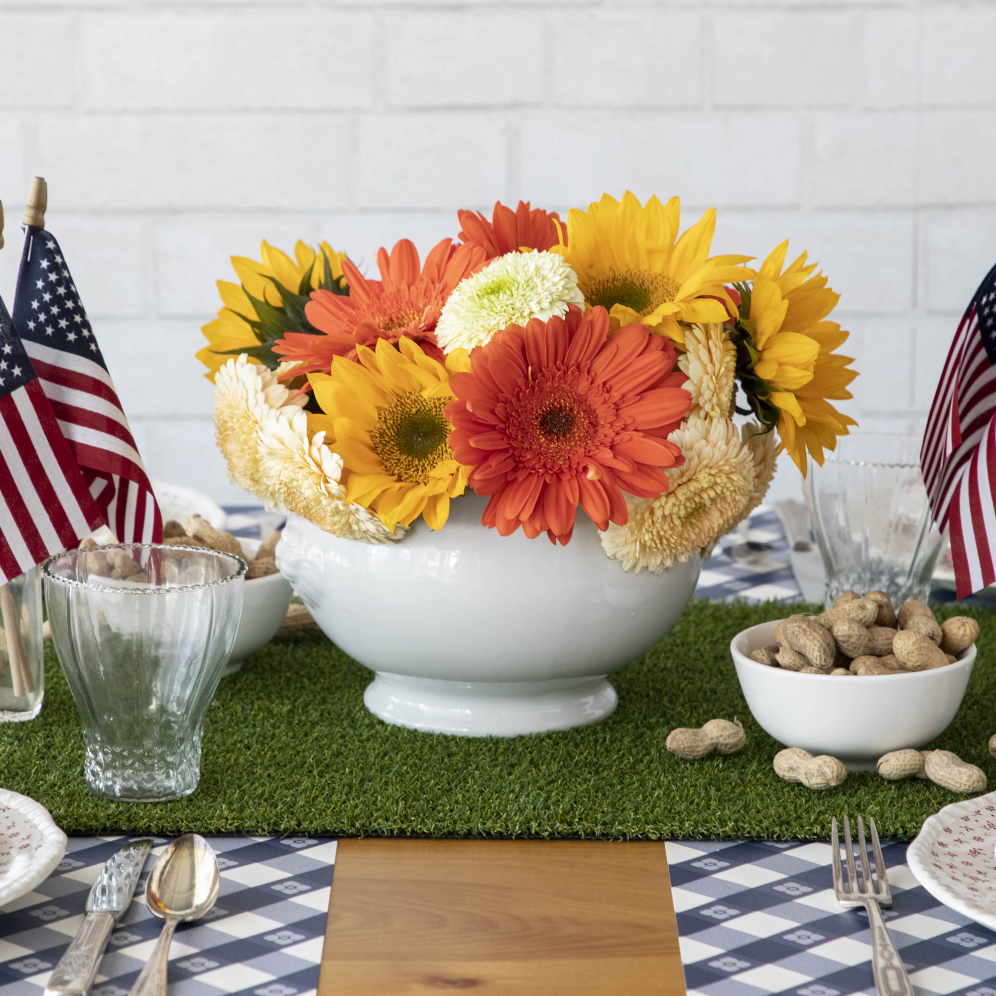 A patriotic table setting adorned with American flags and flowers, enhanced by a Talking Tables Artificial Grass Table Runner for a festive party atmosphere.