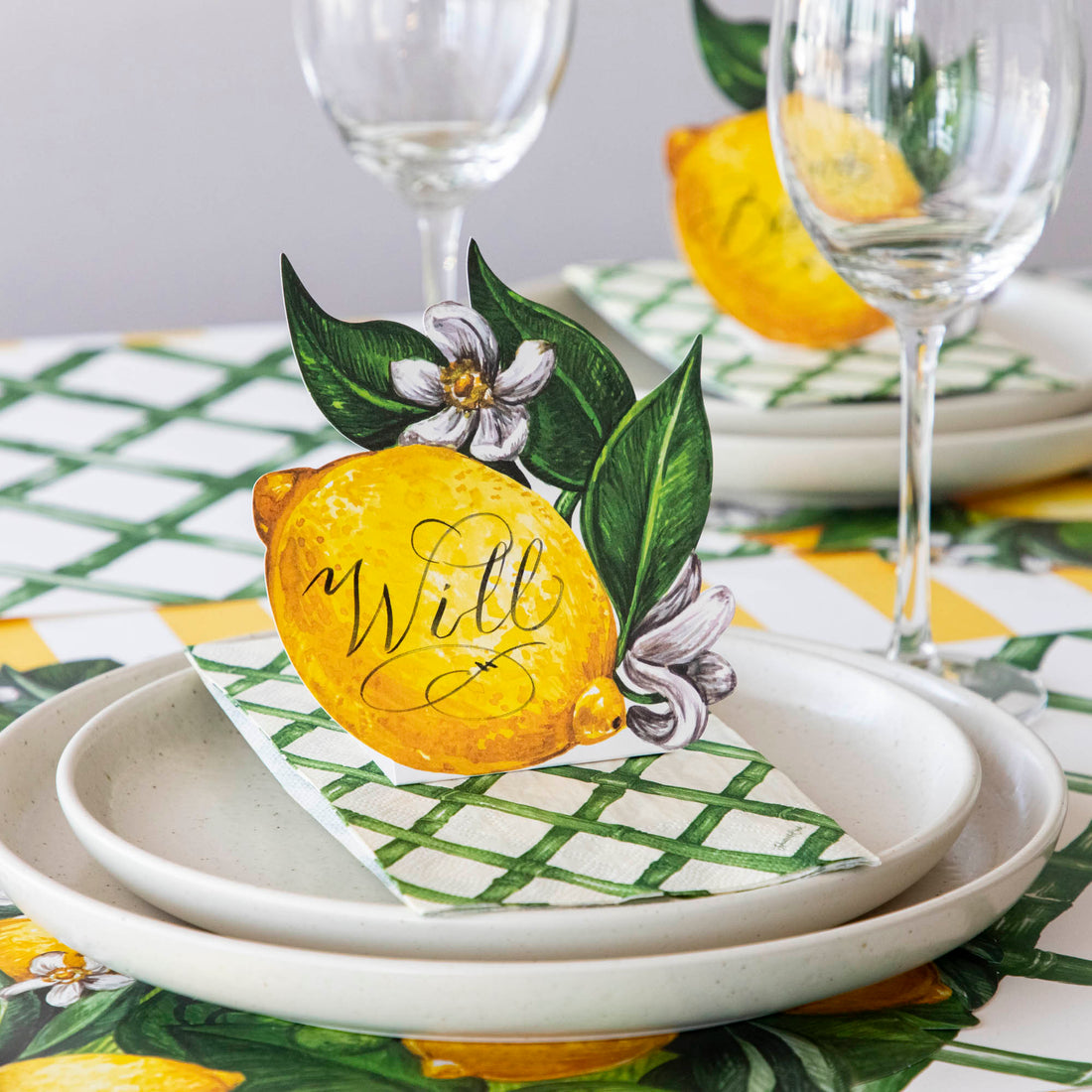 An elegant place setting featuring a Lemon Place Card labeled &quot;Will&quot; standing on the plate.