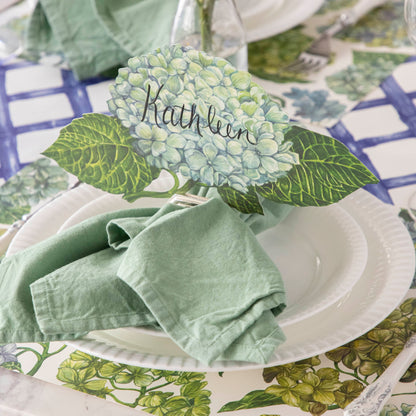 An elegant floral place setting featuring a Hydrangea Table Accent labeled &quot;Kathleen&quot; in a napkin ring card holder.