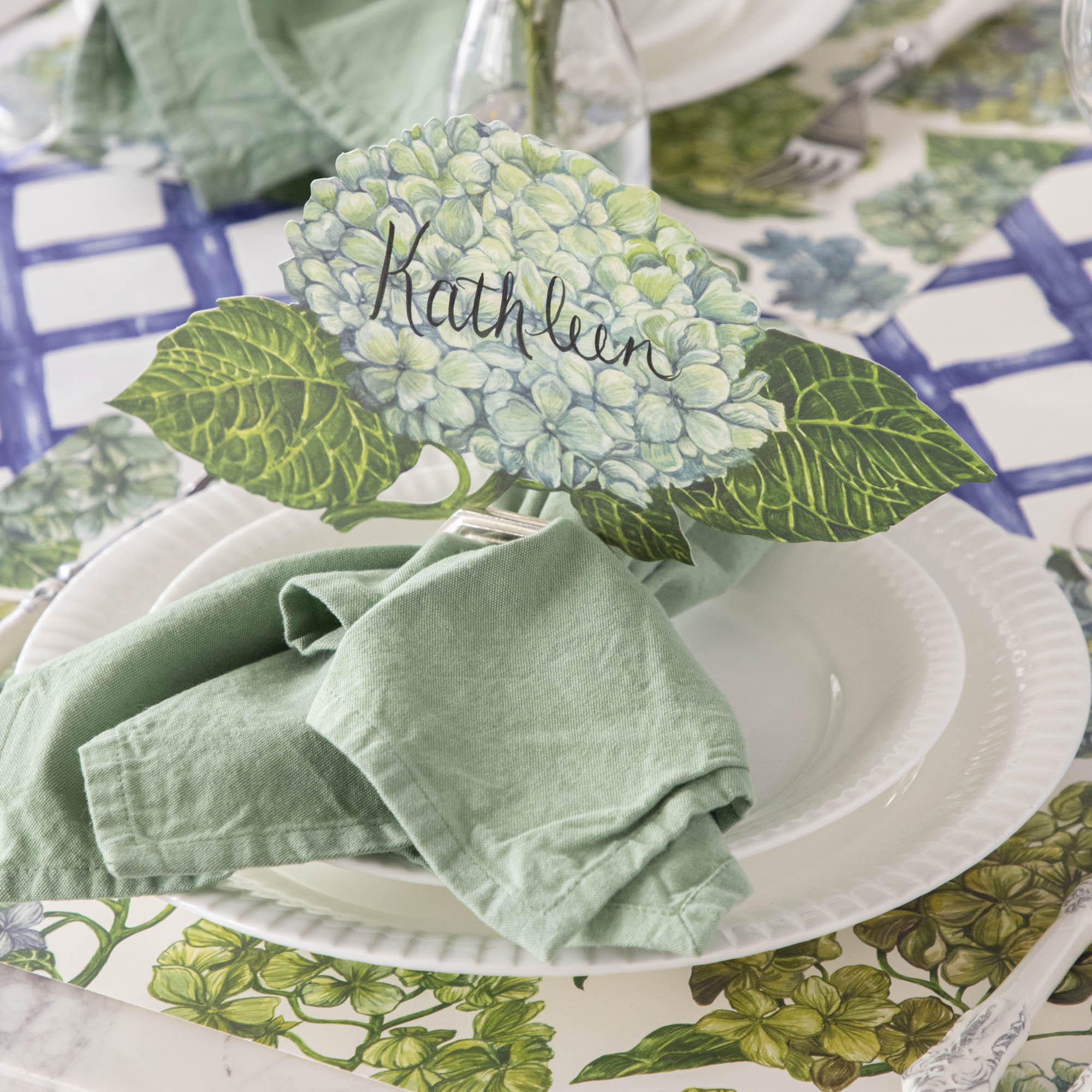 An elegant floral place setting featuring a Hydrangea Table Accent labeled "Kathleen" in a napkin ring card holder.