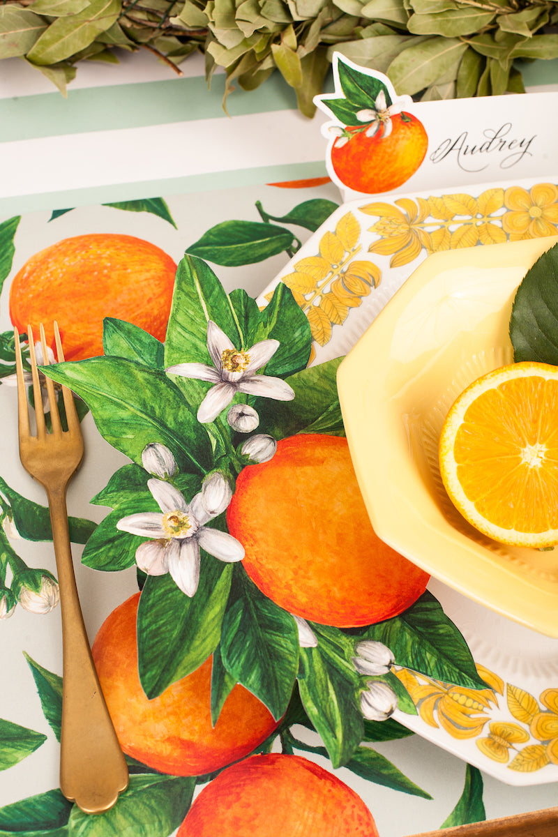 Close-up of an Orange Blossom Table Accent resting on the plate of a citrus-themed place setting.